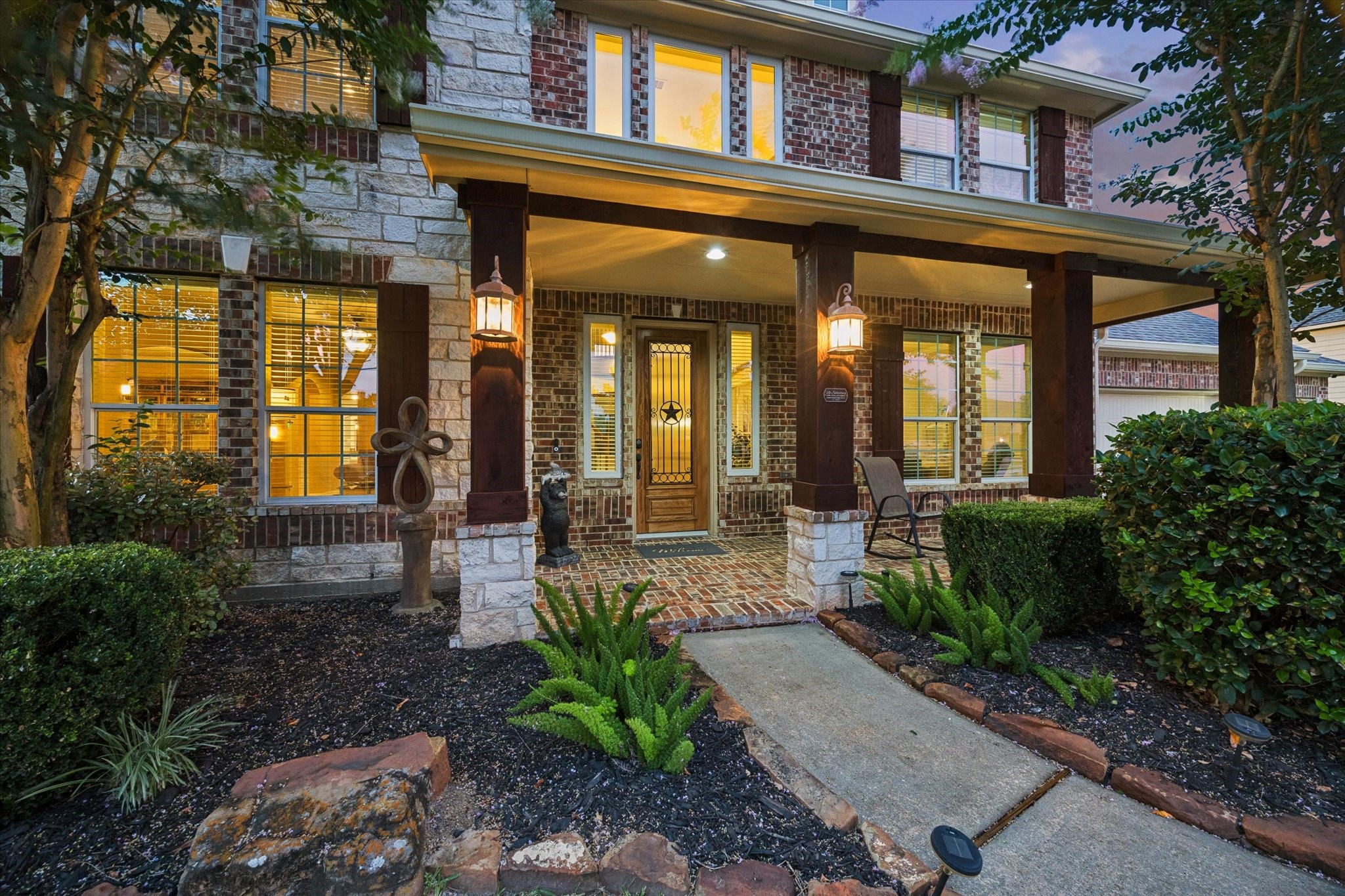 A closer look at the homes beautiful exterior, where classic brick and stone accents create timeless appeal. The inviting covered front porch offers a warm welcome and sets the tone for the exceptional spaces that await inside.