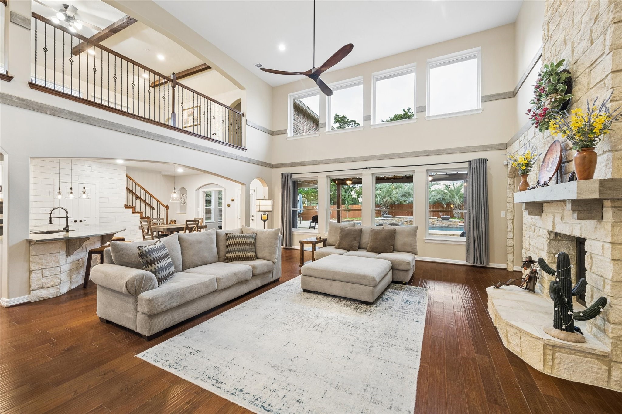 Simply exquisite. Bathed in natural light, this impressive family room showcases soaring ceilings, rich hardwood floors, and a dramatic stone fireplace. Expansive windows frame beautiful views of the pool and outdoor living spaces, while the open-concept design creates a seamless connection to the kitchen and breakfast areaan exceptional setting for both everyday living and entertaining.