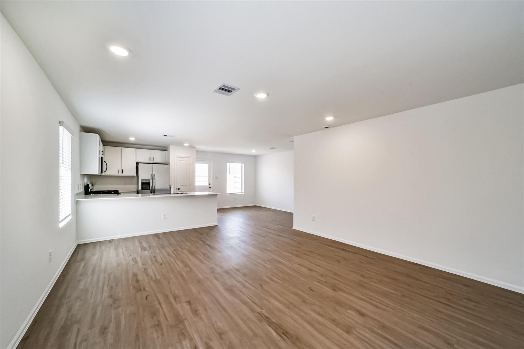 Beautiful open-concept living area connecting seamlessly to the kitchen on the left, featuring a large breakfast bar island with plenty of space for everyday living and entertaining