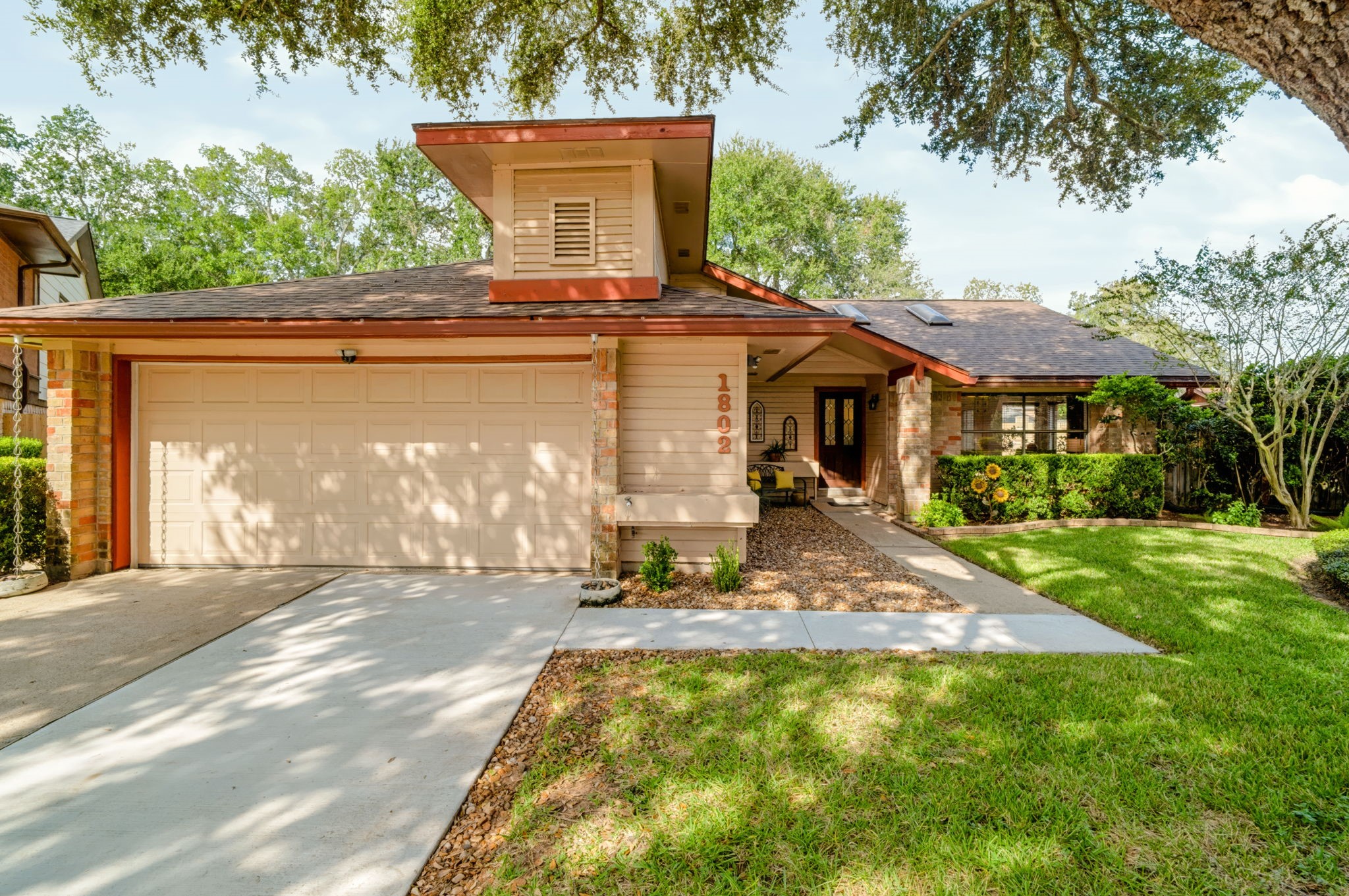 A spacious double-wide driveway leads to the attached two-car garage, offering ample parking. Inside, storage racks provide additional organization, while the floored attic above offers even more storage space.