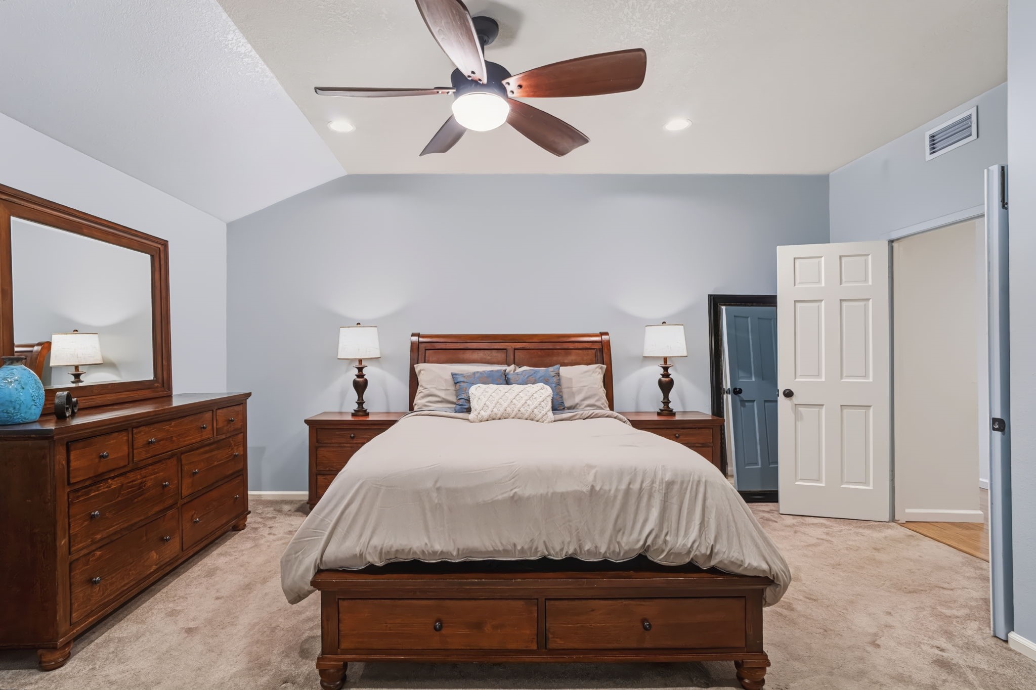 Double doors welcome you into the primary bedroom, featuring recessed lighting, a lighted ceiling fan, and soft, neutral-toned carpeting for a relaxing retreat.