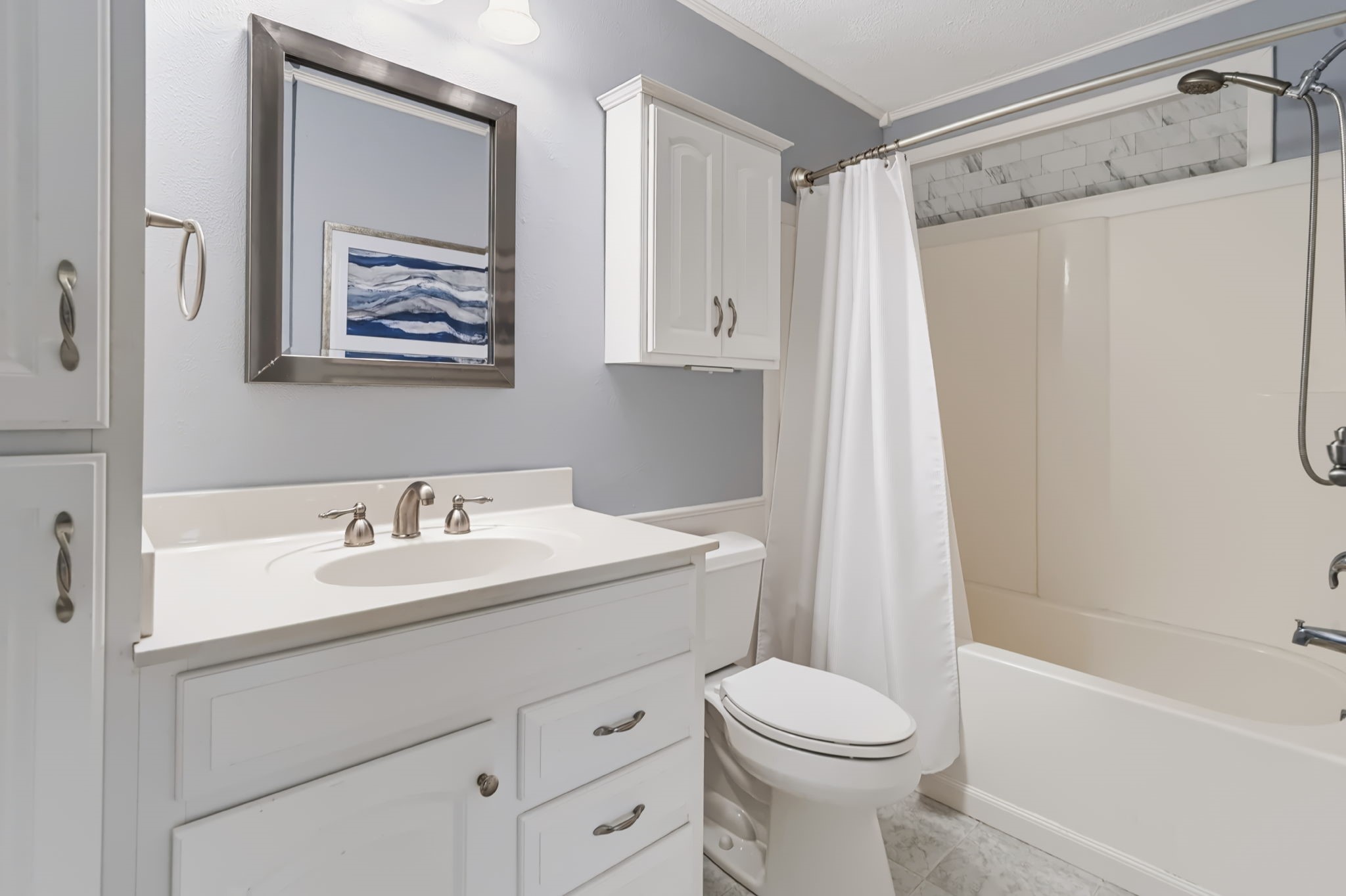 The full hall bathroom features a classic tub/shower combination along with built-in storage to keep everyday essentials neatly organized.