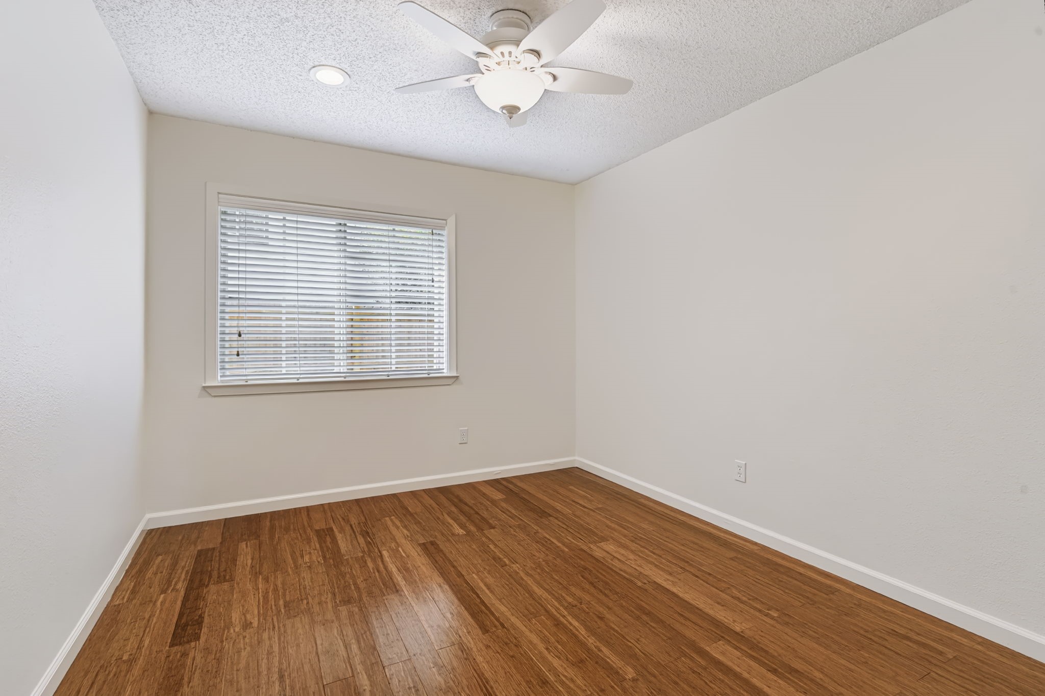 One of two secondary bedrooms, this inviting space features bamboo wood flooring, two closets, a lighted ceiling fan, and a large window that welcomes in natural light.