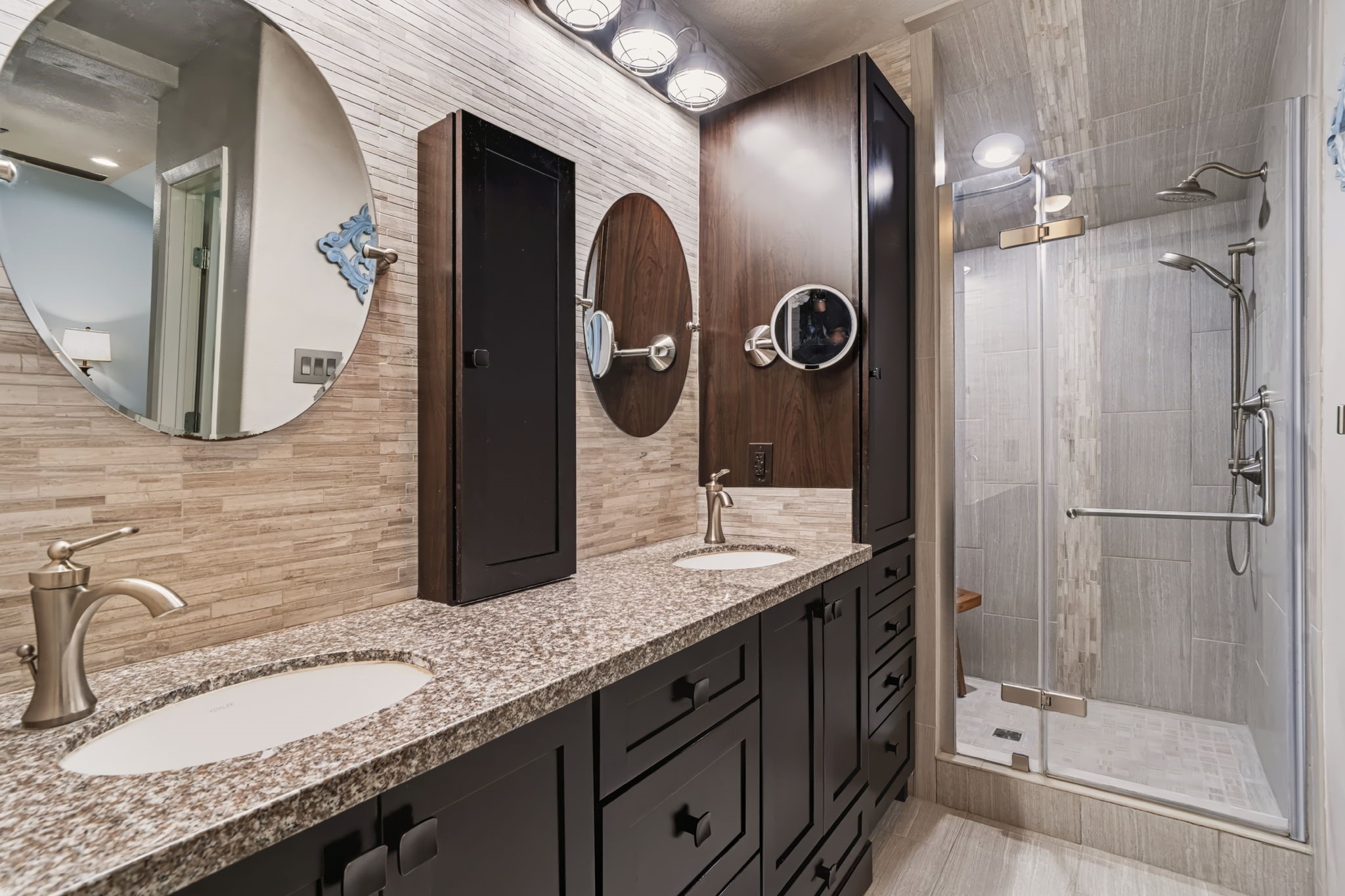 The renovated primary bath features a large dual vanity with generous storage and a frameless glass walk-in shower, complete with a rain showerhead and handheld sprayer for a spa-like experience. The adjoining walk-in closet offers built-in storage to keep everything organized.