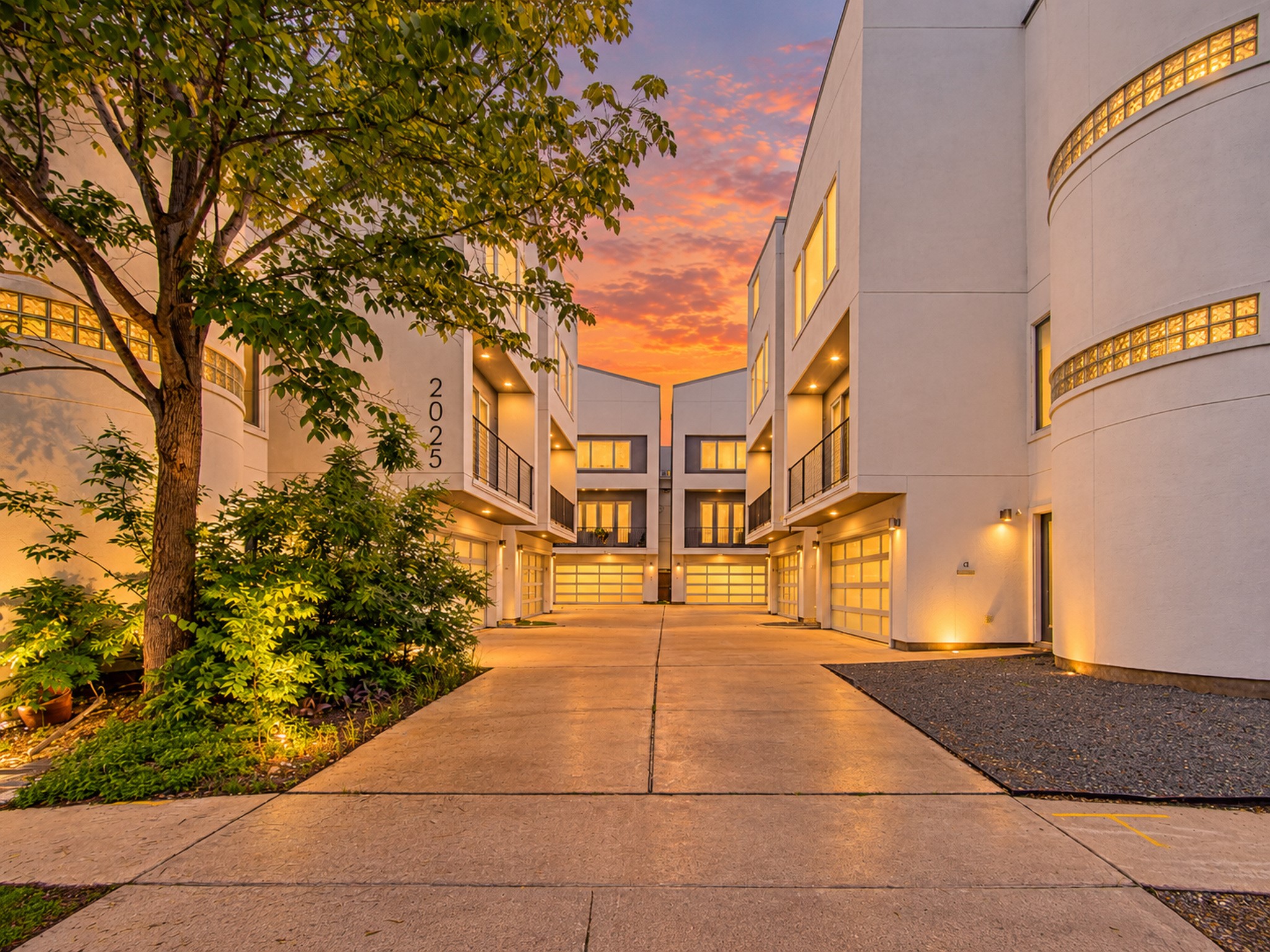 Gated driveway leading into the community, with illuminated architectural details and landscaped surroundings.