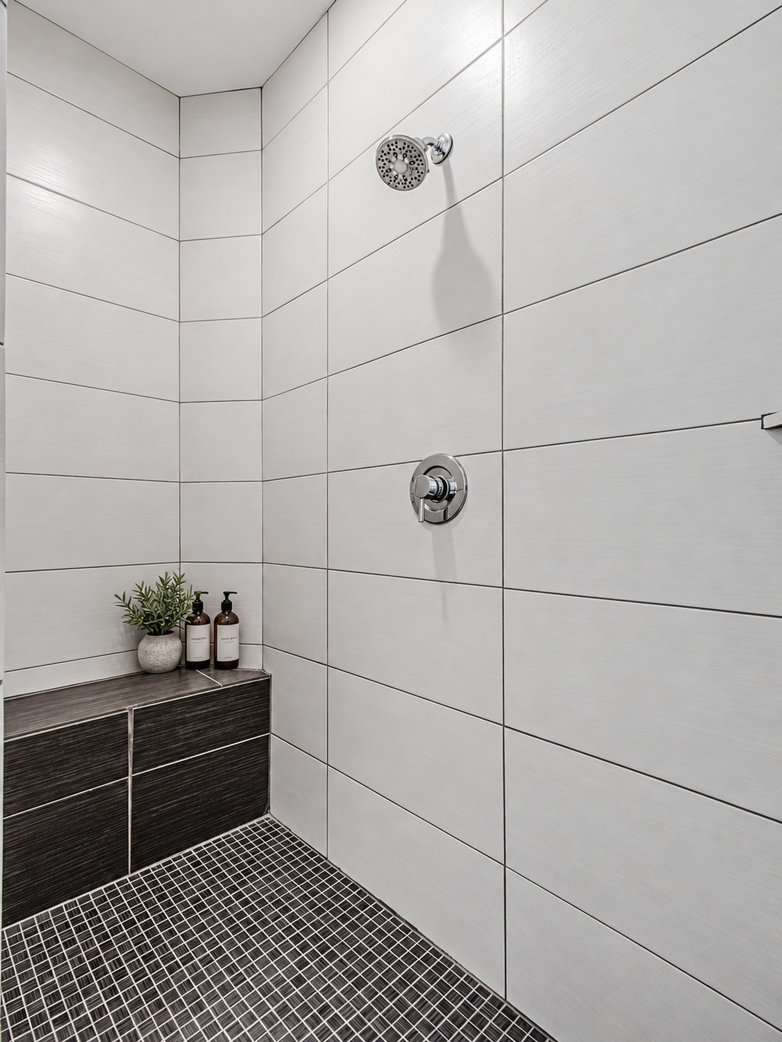 Walk-in shower featuring large-format wall tile, contrasting floor tile, and a built-in bench.