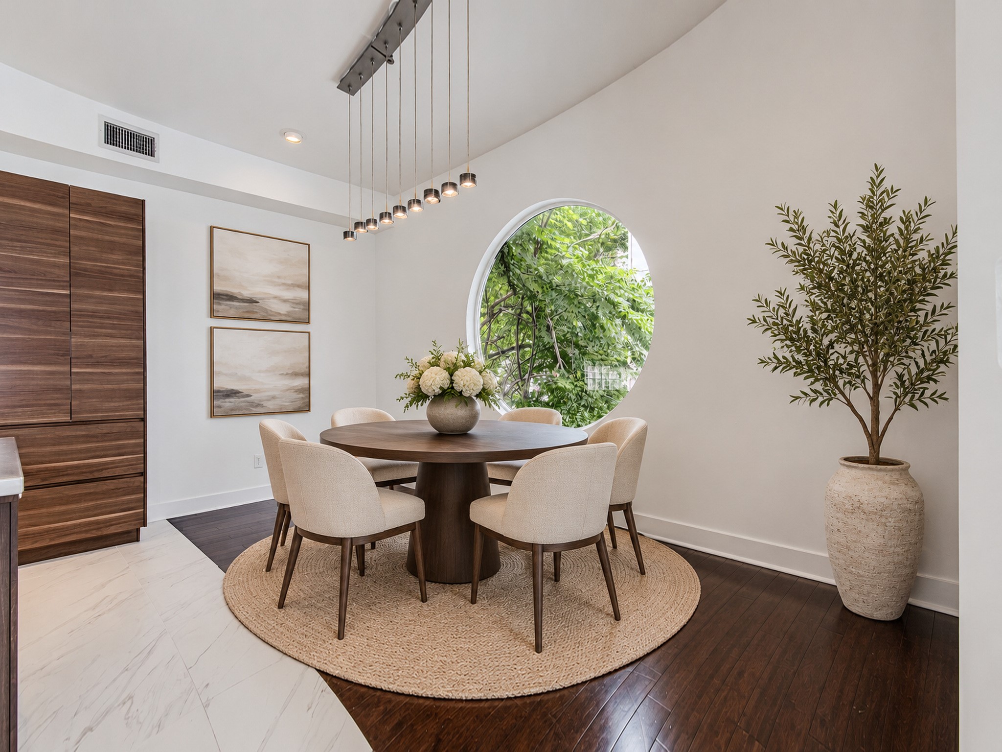 Dining area framed by a distinctive circular window, with wood flooring and convenient access to the kitchen.
