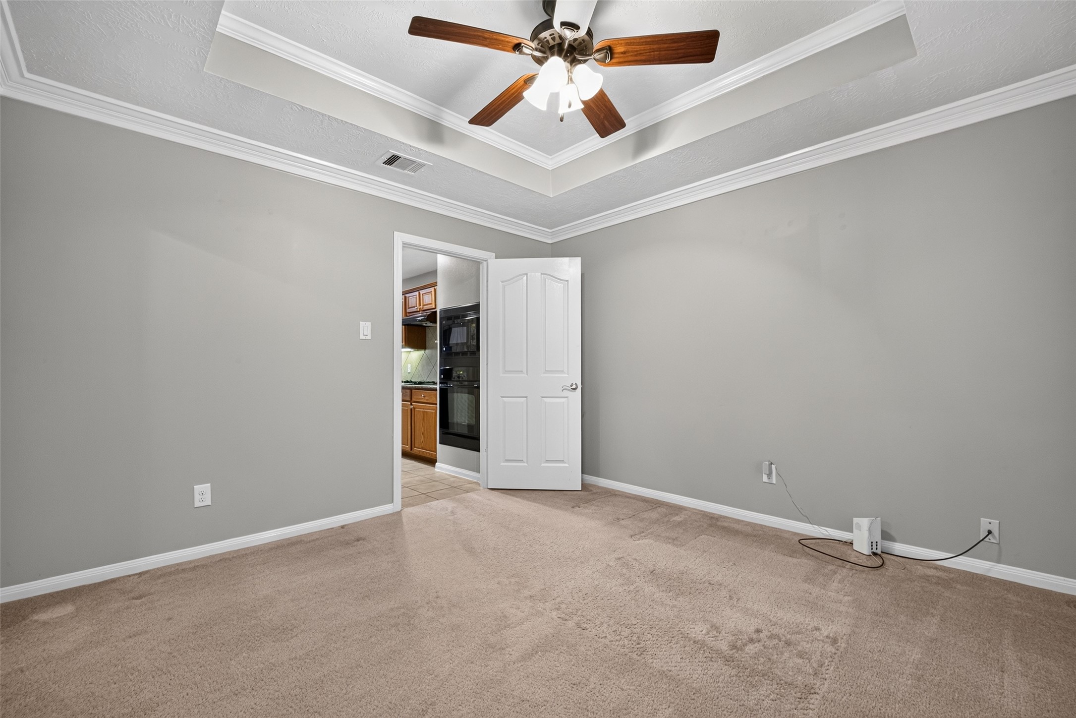 Spacious flex area with a coffered ceiling, ceiling fan, and carpeted flooring.