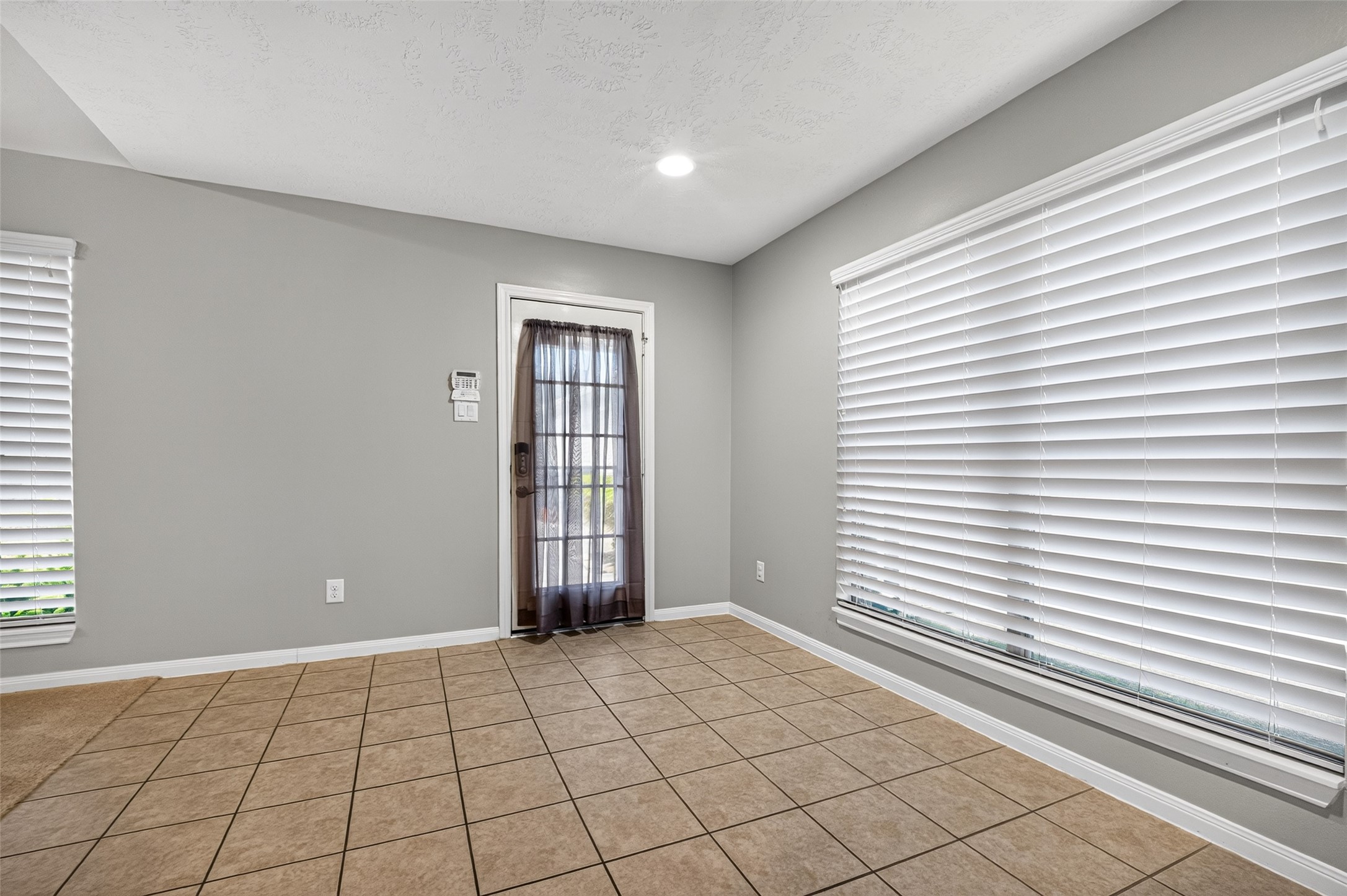 Additional breakfast-area view highlights windows on two walls, tile flooring, recessed lighting, and an exterior door with a glass insert.