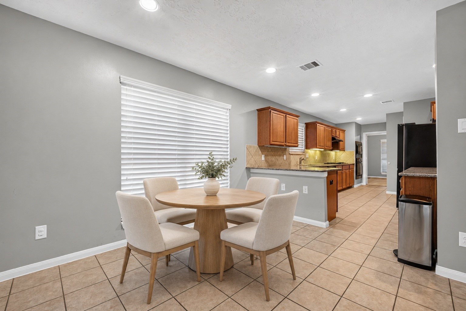 Virtually staged breakfast area showcases space for a dining table beside the large window, with tile flooring and direct access to the kitchen. Virtually staged breakfast area showcases space for a dining table beside the large window, with tile flooring and direct access to the kitchen.