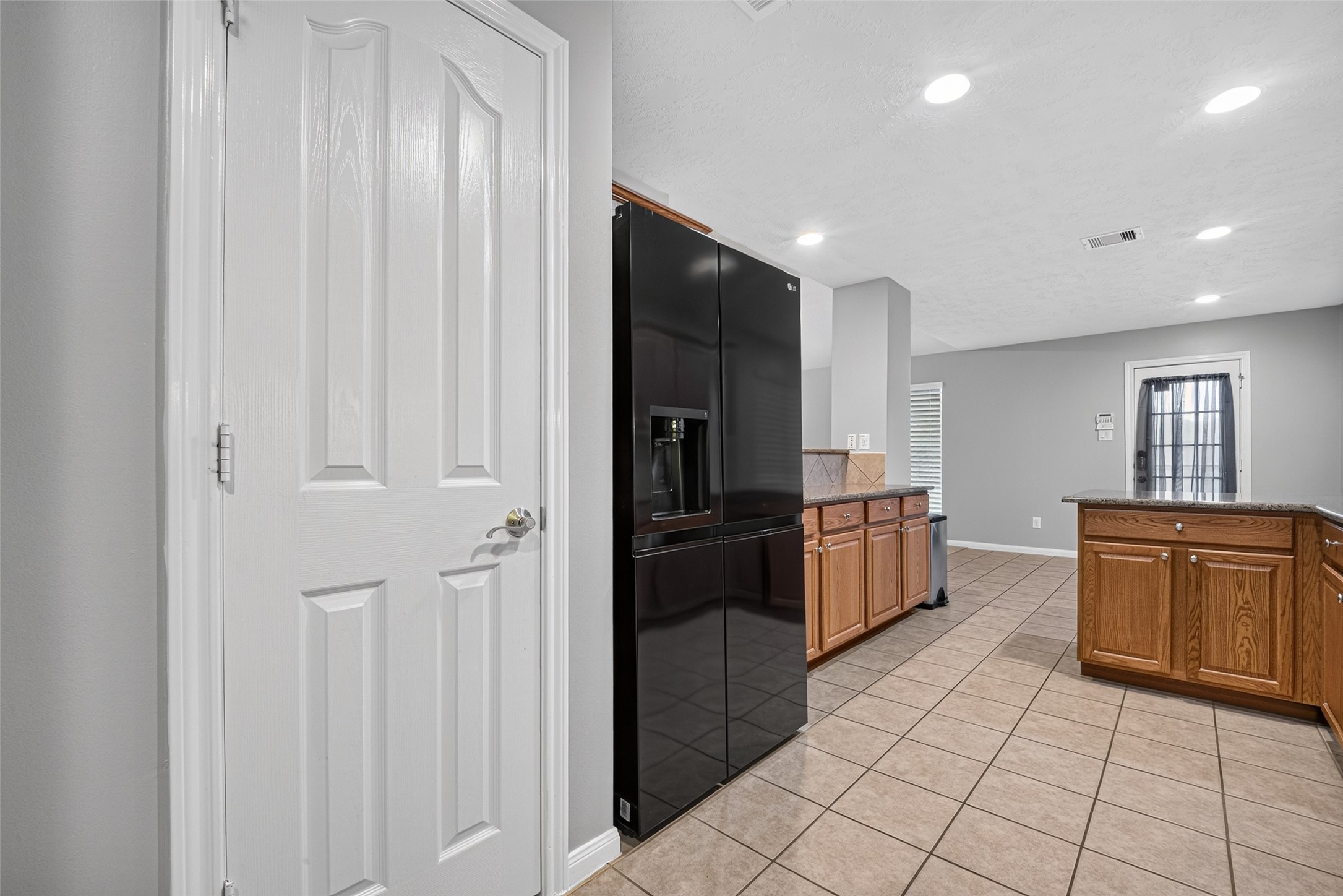 Kitchen with tile flooring, wood cabinetry, black appliances, and ample counter space.