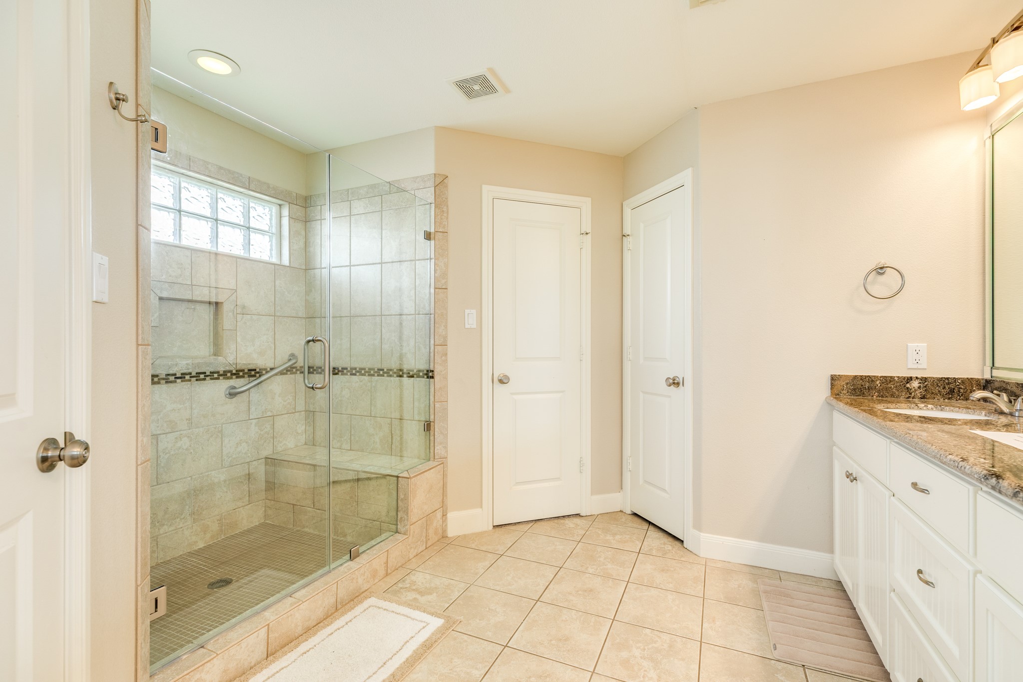 View of the primary walk in shower, door to the left is 'her' closet and door next to this is the water closet.