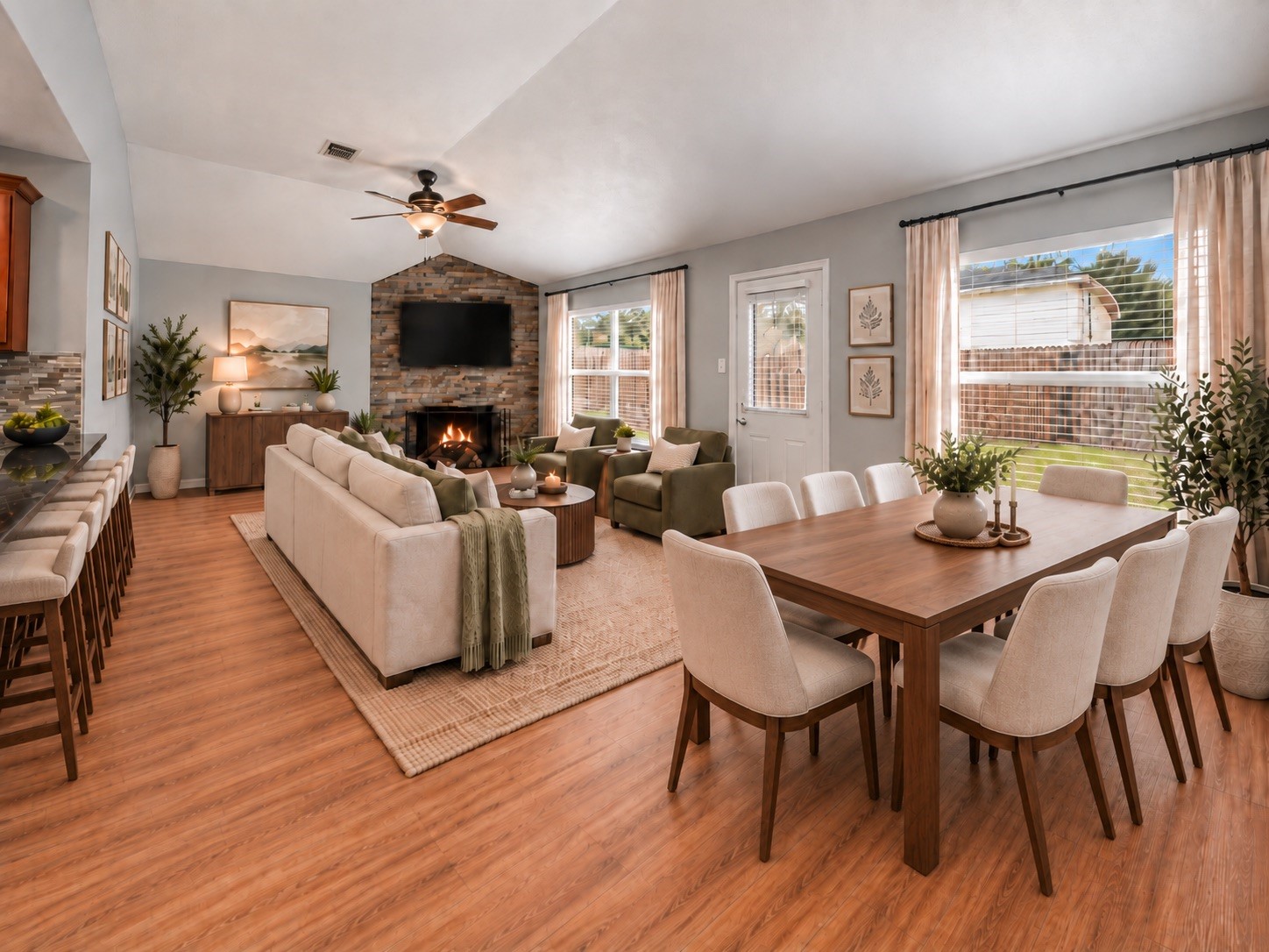 Virtually staged family and dining area highlights the rooms spacious layout, high ceiling, and fireplace.