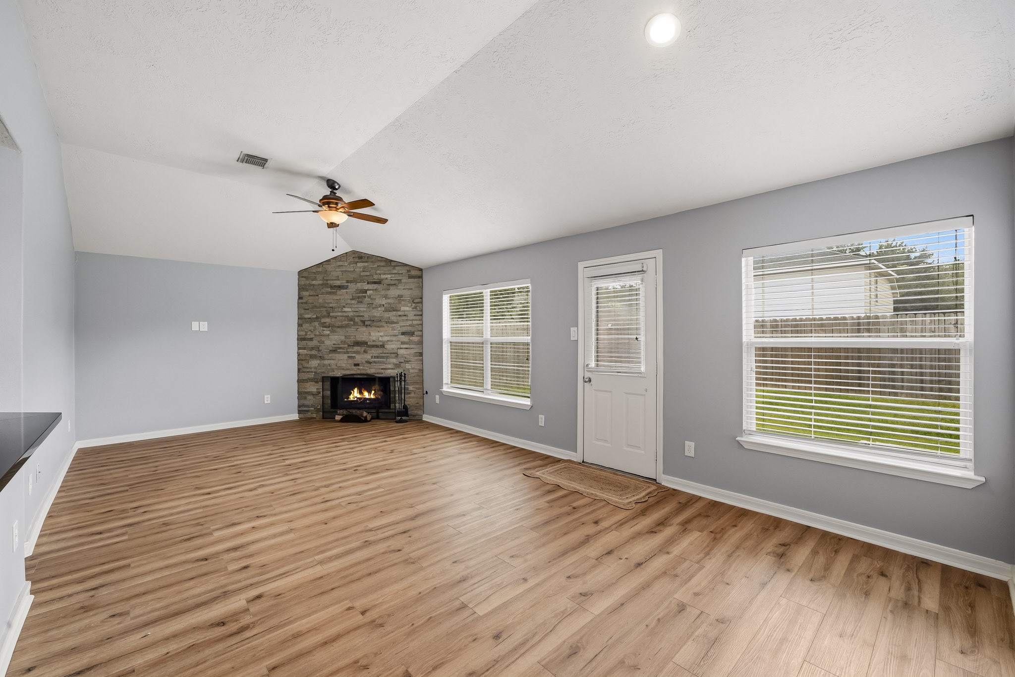 Spacious family area features warm flooring, high ceilings, and a cozy corner fireplace.