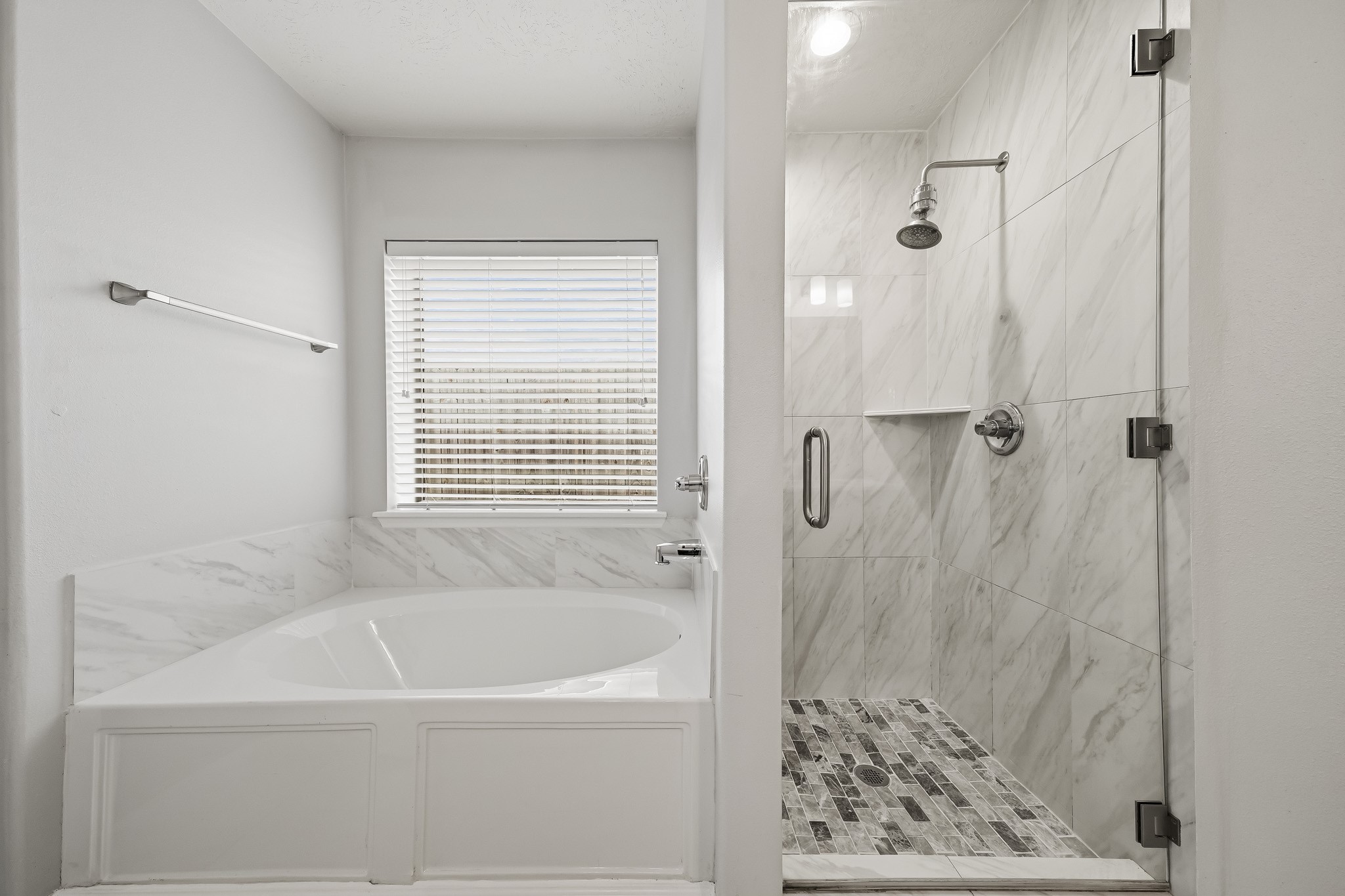 Separate glass-enclosed shower and soaking tub create a relaxing primary bath retreat.