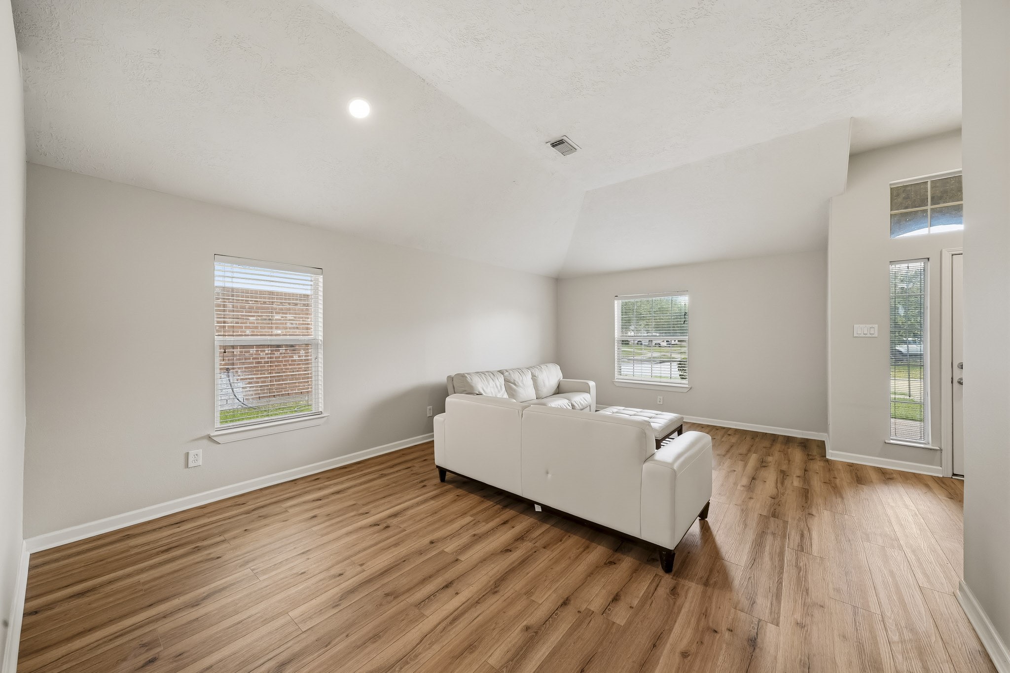 Spacious flex area features warm flooring and multiple windows for natural light.