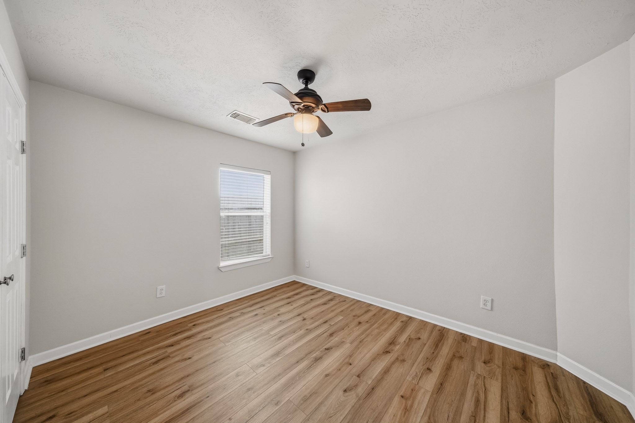 Secondary bedroom features neutral finishes, warm flooring, and natural light.