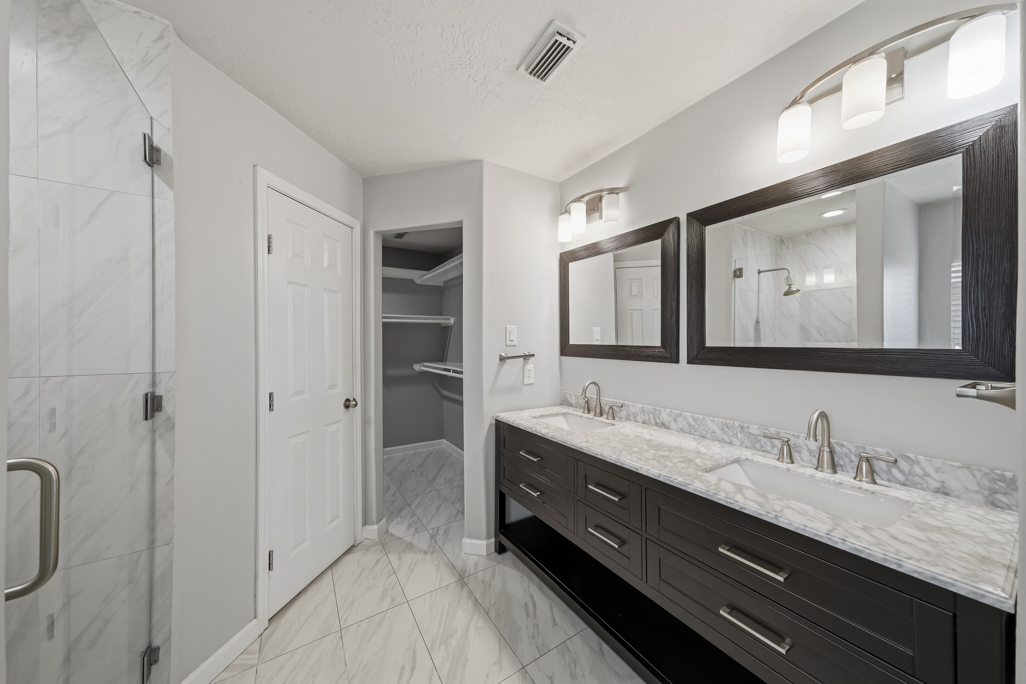 Updated primary bath features a long dual-sink vanity with modern finishes.
