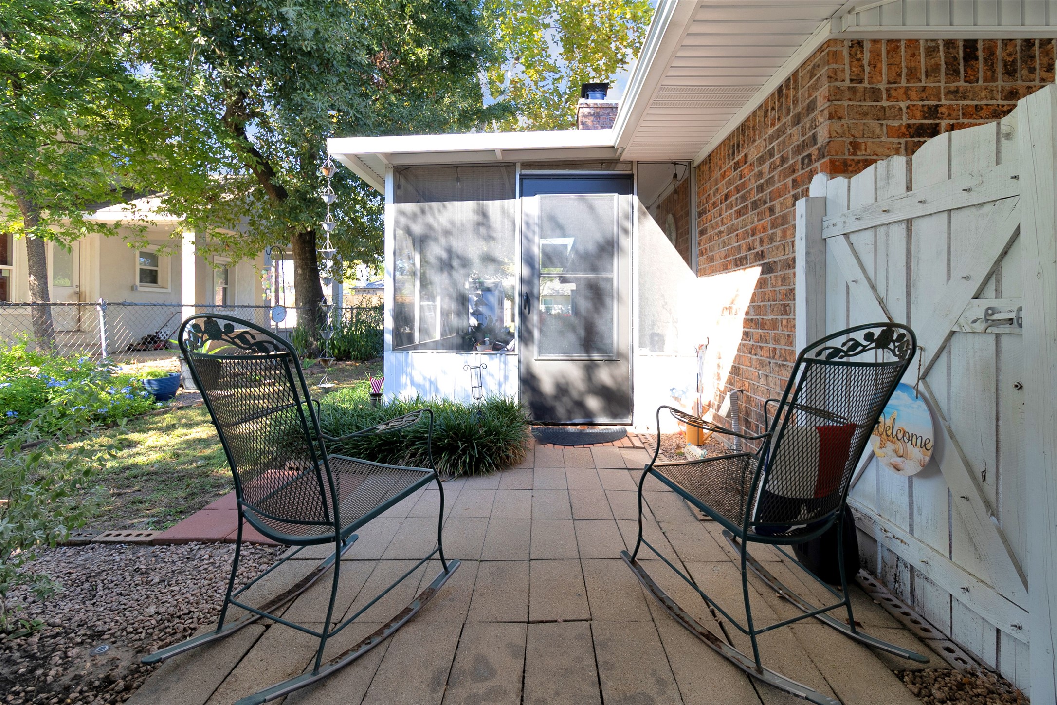 Charming patio area featuring a cozy seating arrangement with metal rocking chairs, surrounded by lush greenery and a welcoming atmosphere.