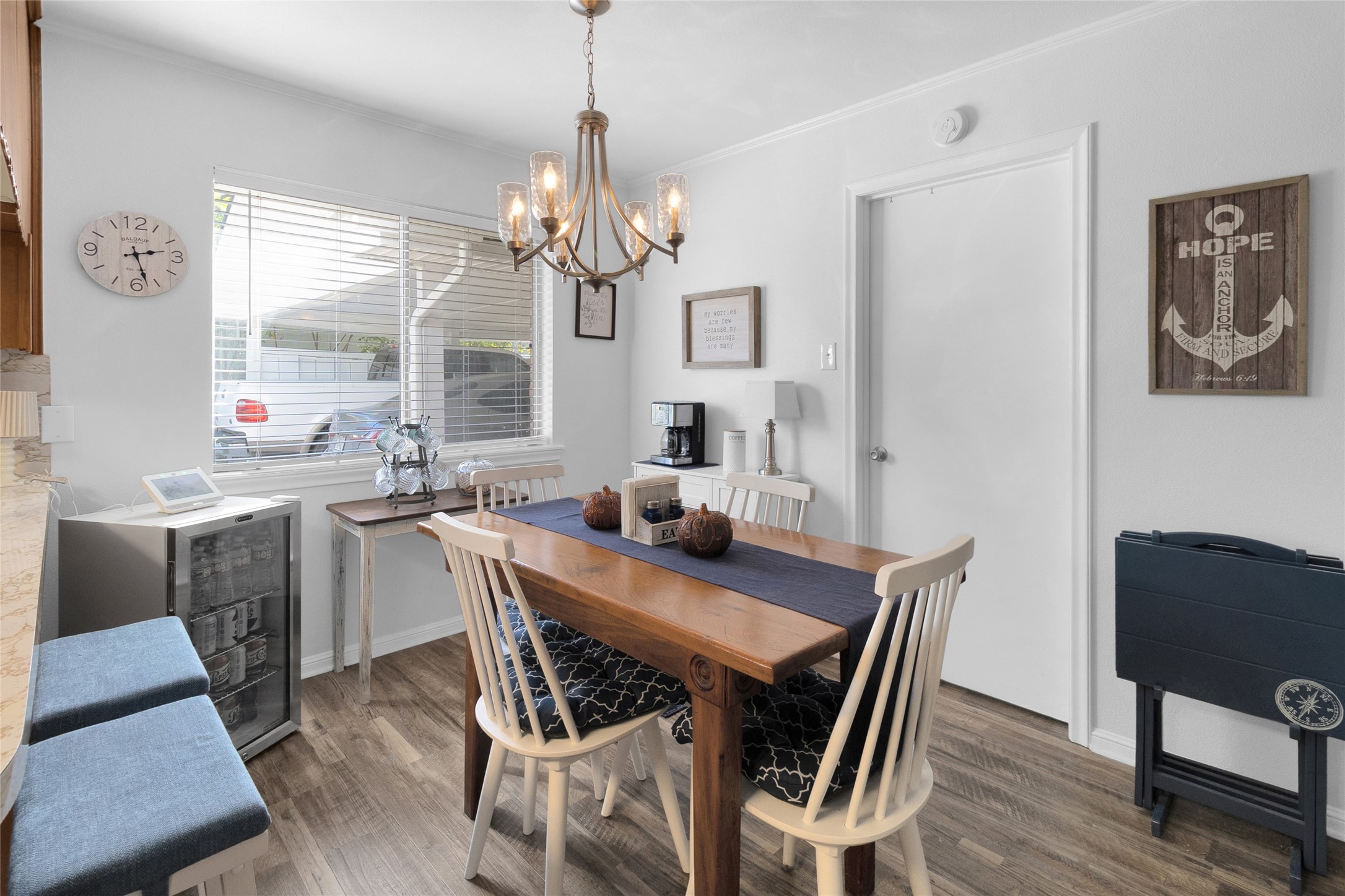 Cozy breakfast area with warm wood flooring, a charming chandelier, and ample natural light from a large window, perfect for intimate gatherings.