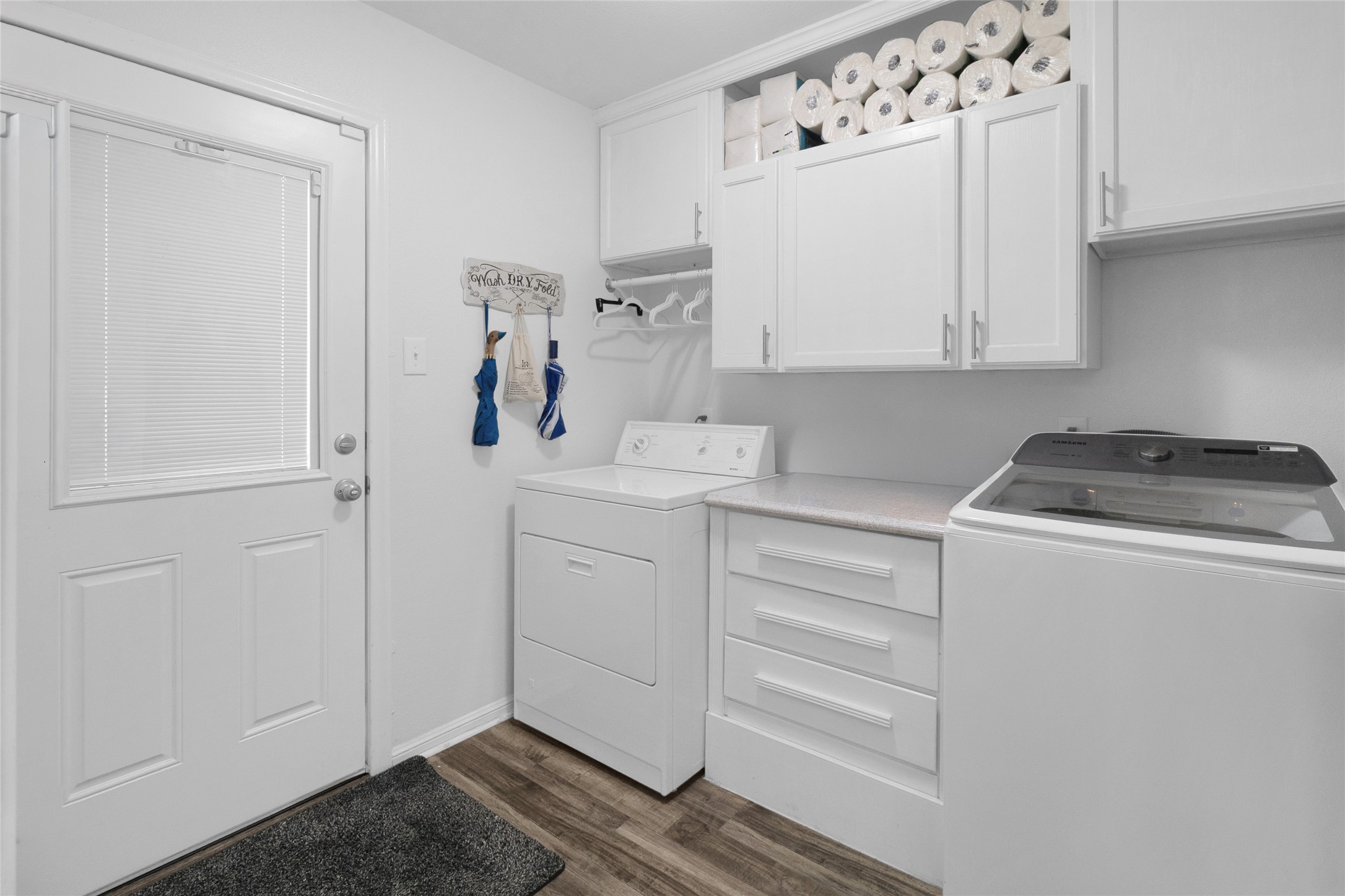 Bright and efficient laundry room with ample storage, featuring upper cabinets filled with essentials and modern appliances for all your laundry needs.