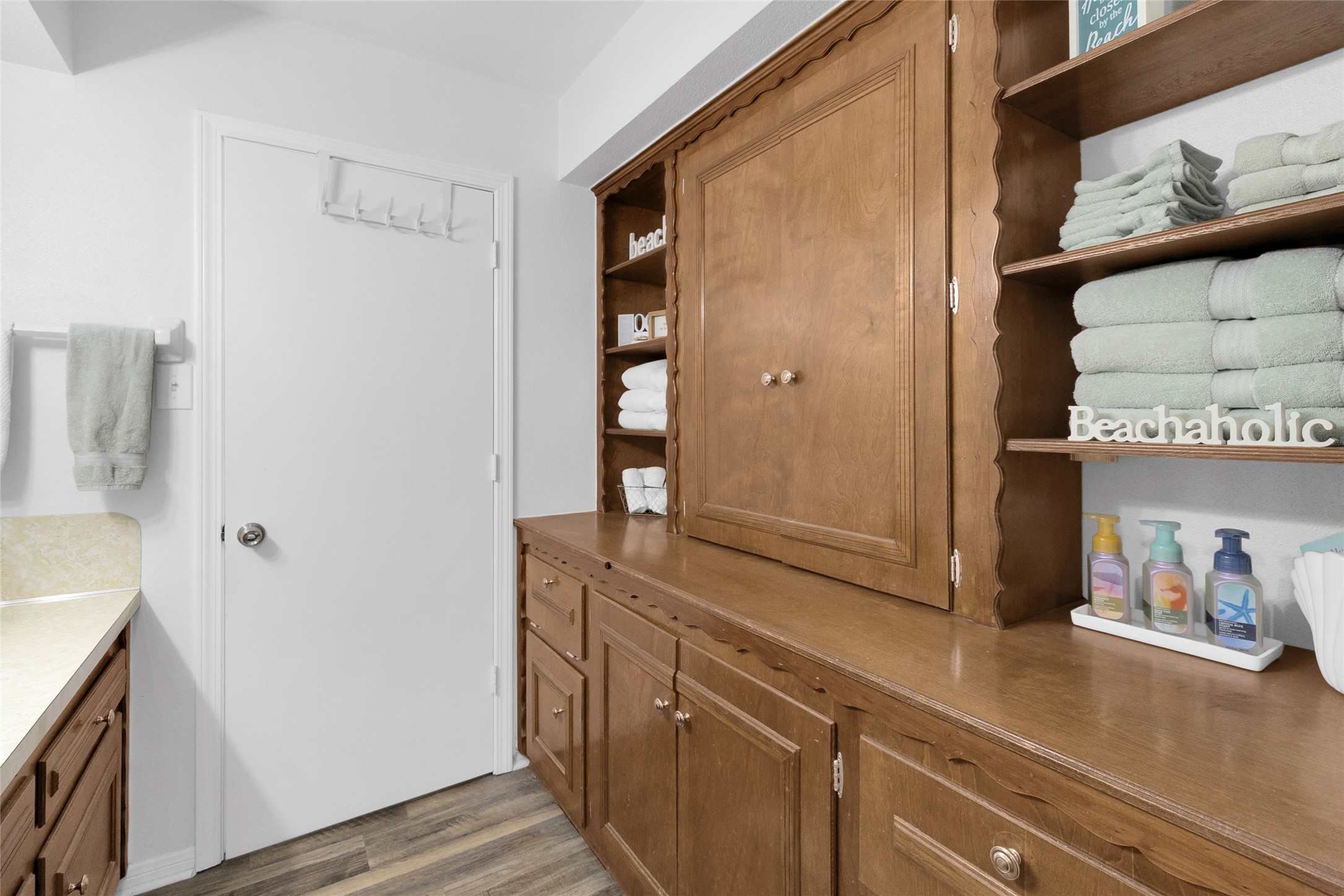 Charming bathroom with ample wooden cabinetry, open shelving, and neatly arranged towels, offering both style and functionality.