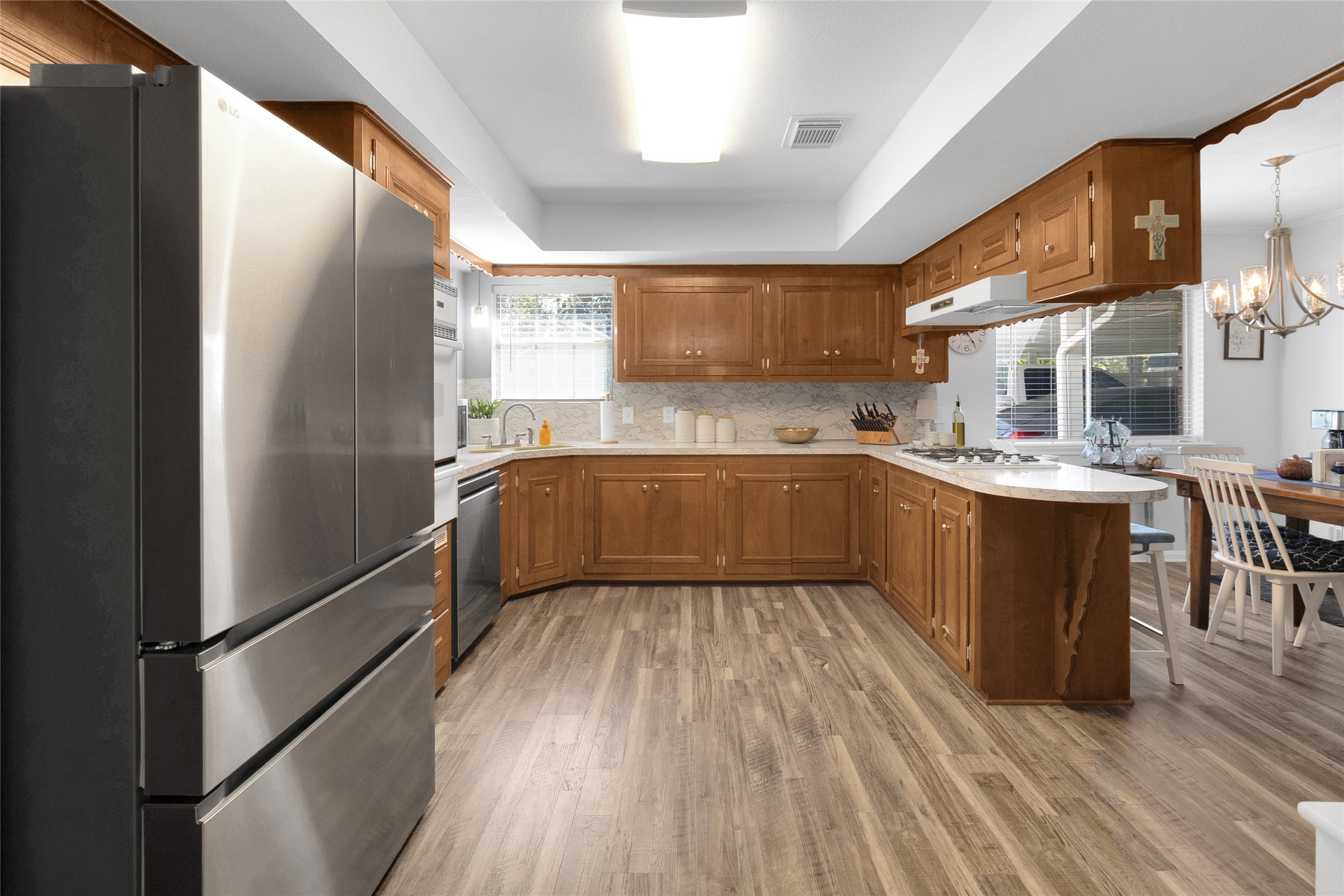 Spacious kitchen featuring sleek stainless steel appliances, warm wooden cabinetry, and a cozy breakfast bar, seamlessly connected to the breakfast area for effortless entertaining.