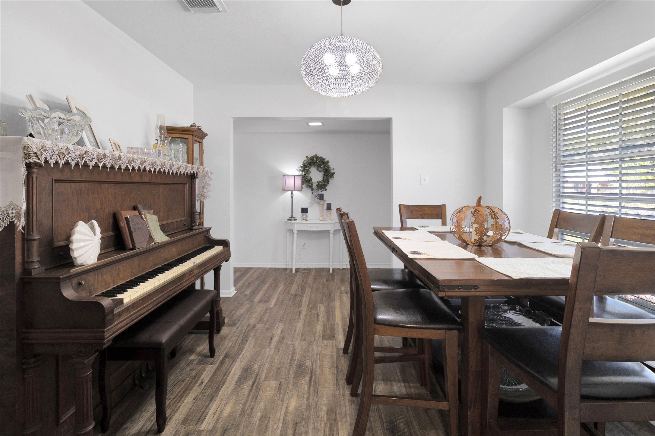 Charming dining area featuring a classic wood piano and a large window that fills the room with natural light, creating a warm and inviting atmosphere for gatherings.