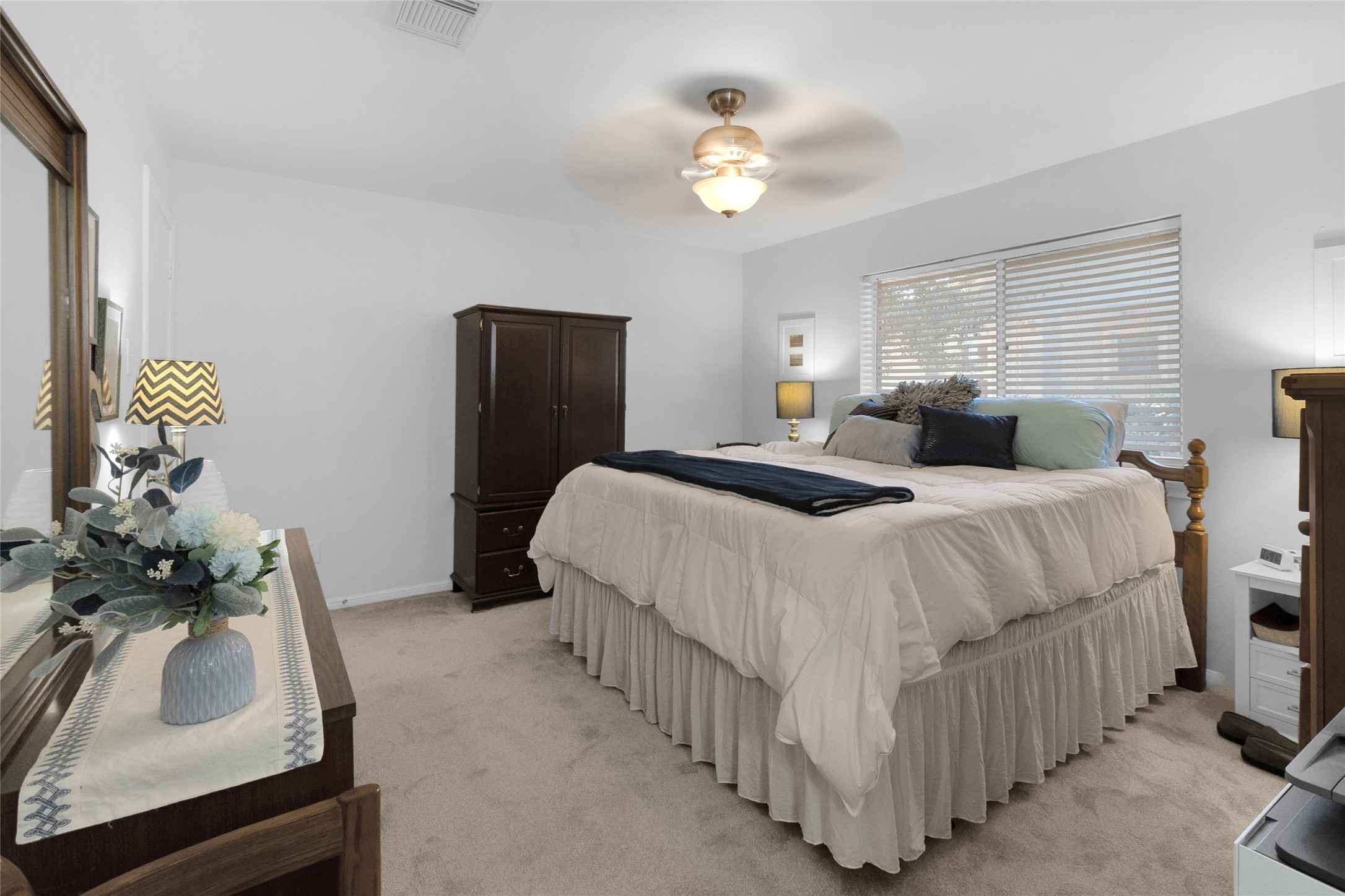 Angled view of the bedroom with soft carpeting, a comfortable bed, and ample natural light from large windows.