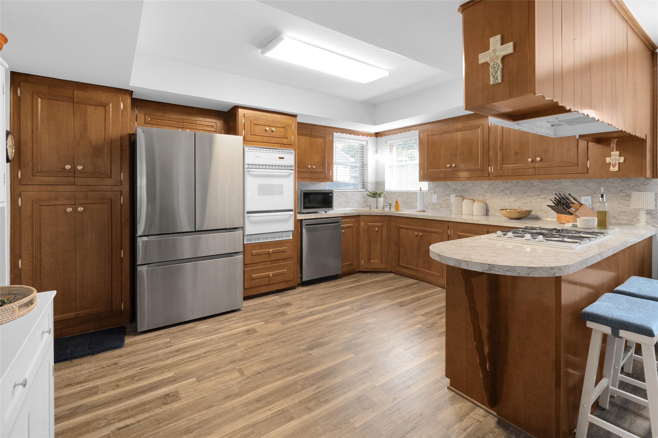 Spacious kitchen with warm wooden cabinetry, stainless steel appliances, and a large countertop with seating, perfect for cooking and entertaining.