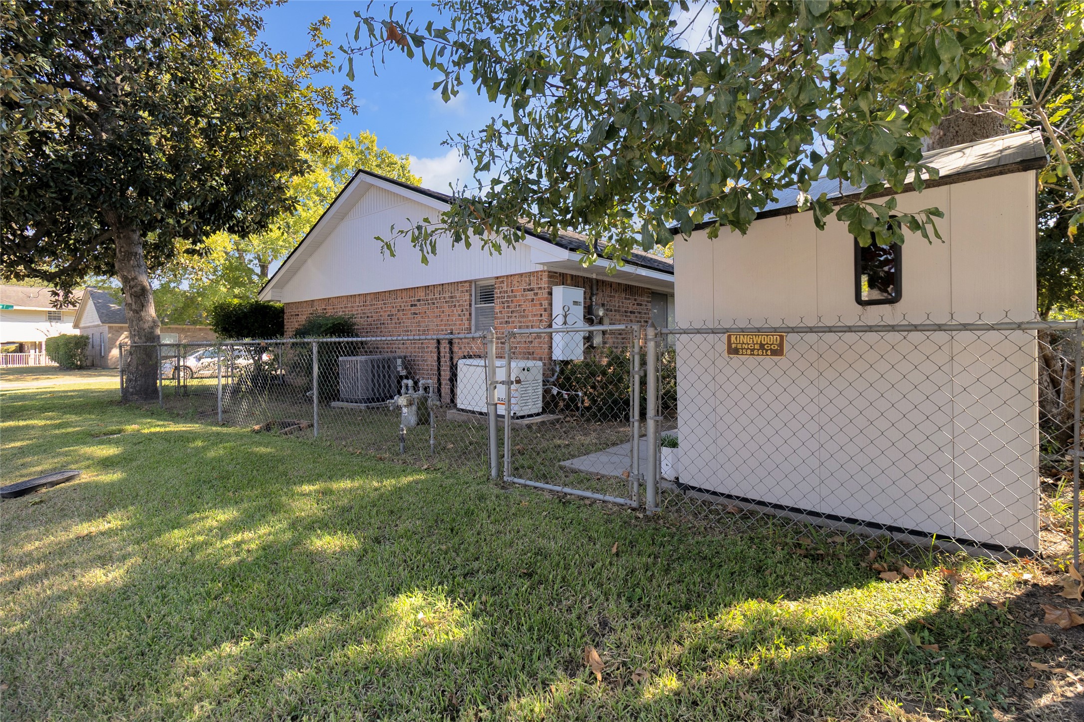 Charming brick home with a fenced yard, mature trees, and a convenient storage shed, offering a perfect blend of privacy and utility.