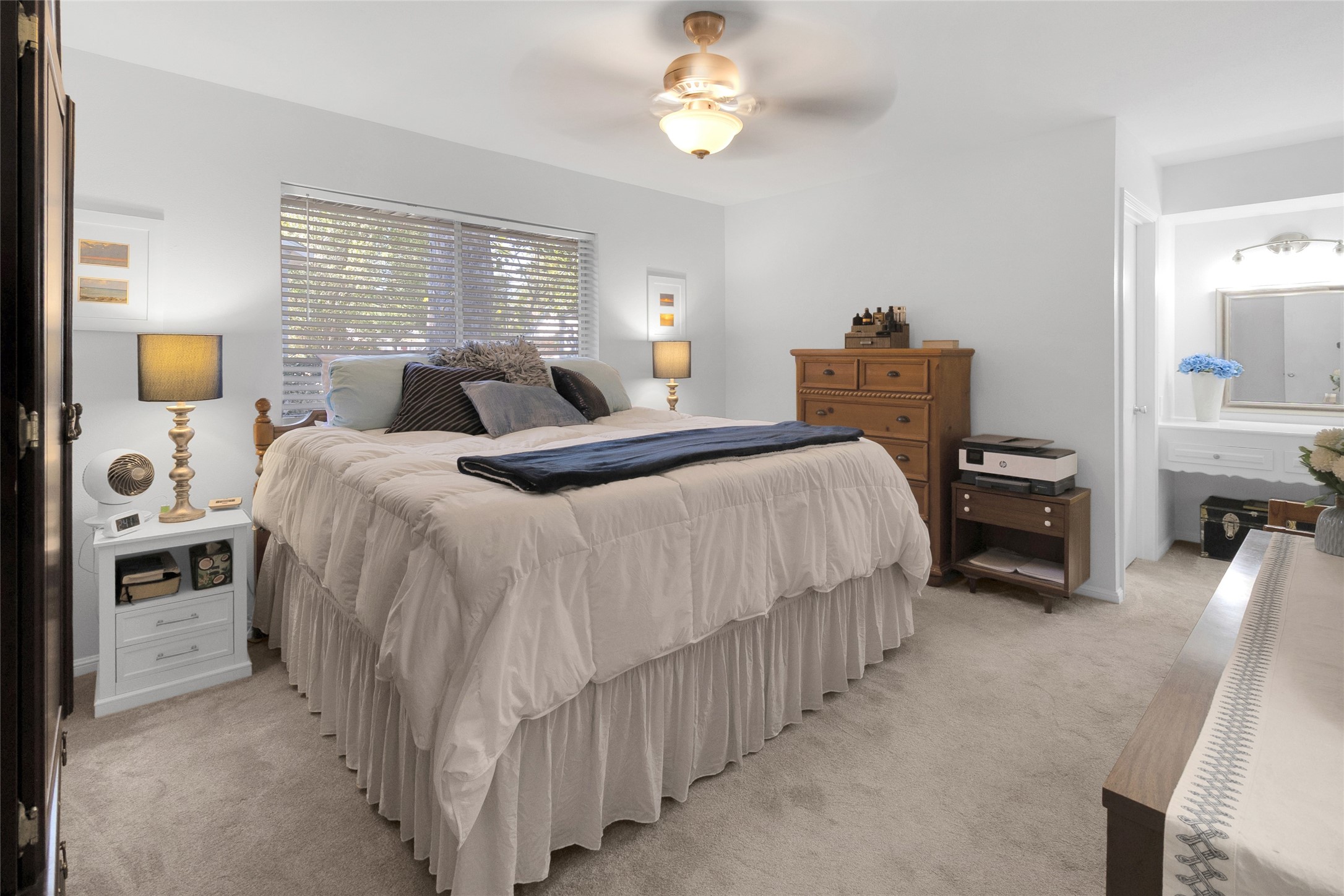 Primary bedroom featuring a plush, inviting bed, warm wood accents, and ample natural light from a large window, creating a tranquil retreat.
