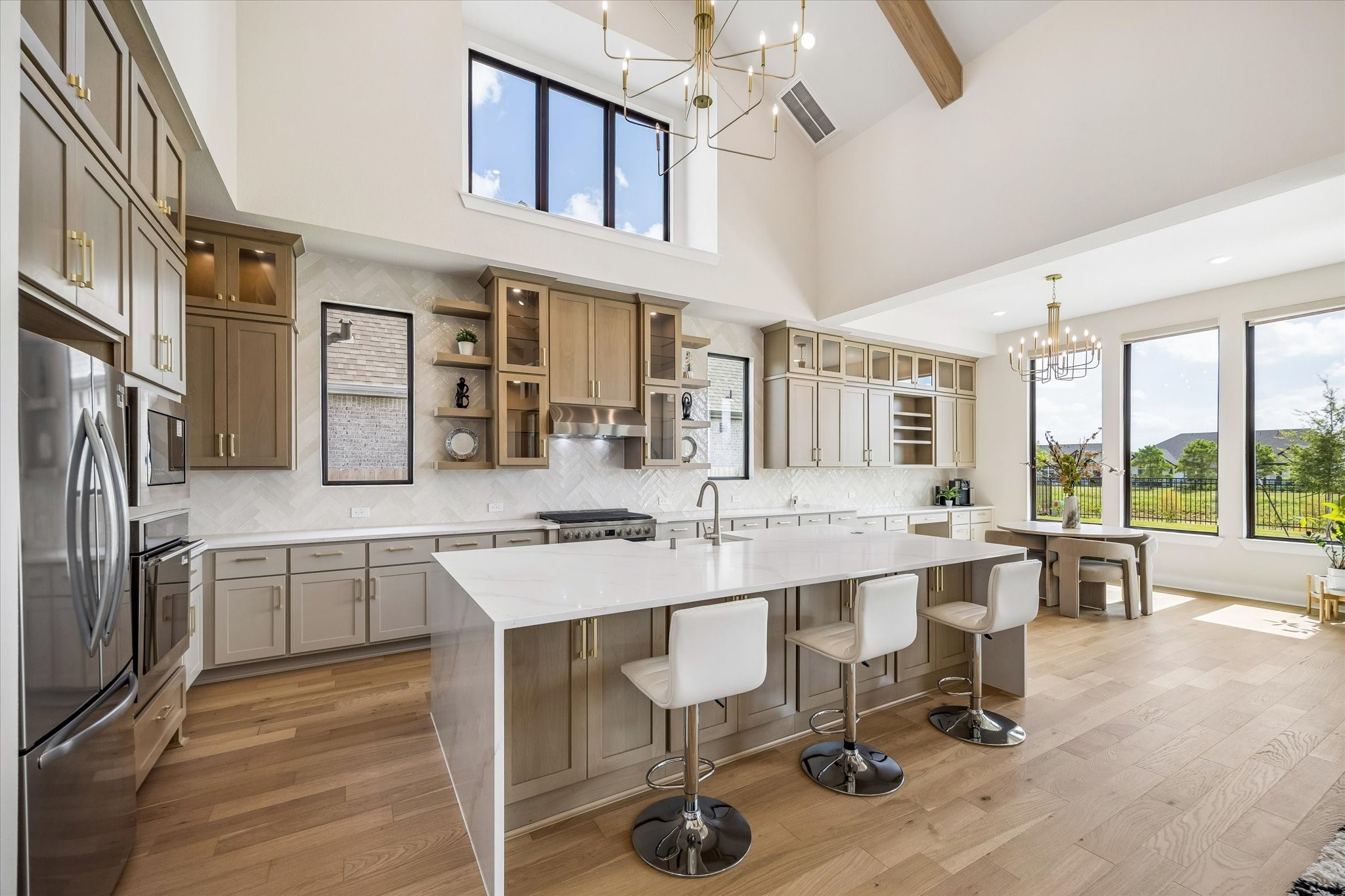 SPACIOUS KITCHEN FEATURES EXTENSIVE CABINETRY, QUARTZ COUNTERTOPS, AN OVERSIZED ISLAND WITH SEATING, STAINLESS STEEL APPLIANCES, AND A BRIGHT ADJOINING BREAKFAST AREA.