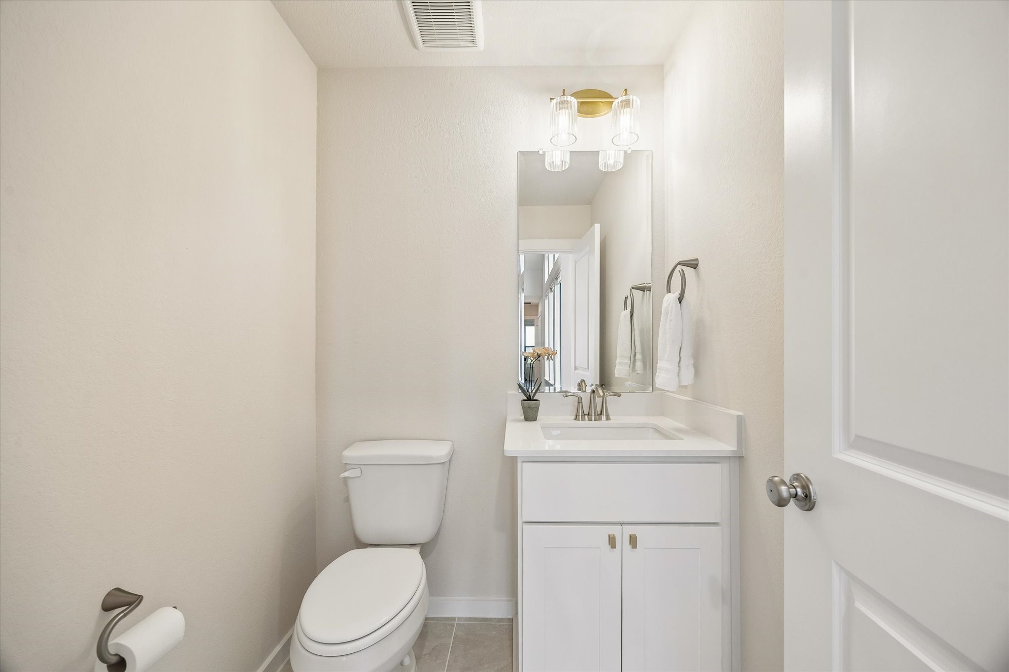 UPSTAIRS POWDER BATH FEATURES A CLEAN, MODERN DESIGN WITH A QUARTZ VANITY, FRAMED MIRROR, AND UPDATED LIGHTING.