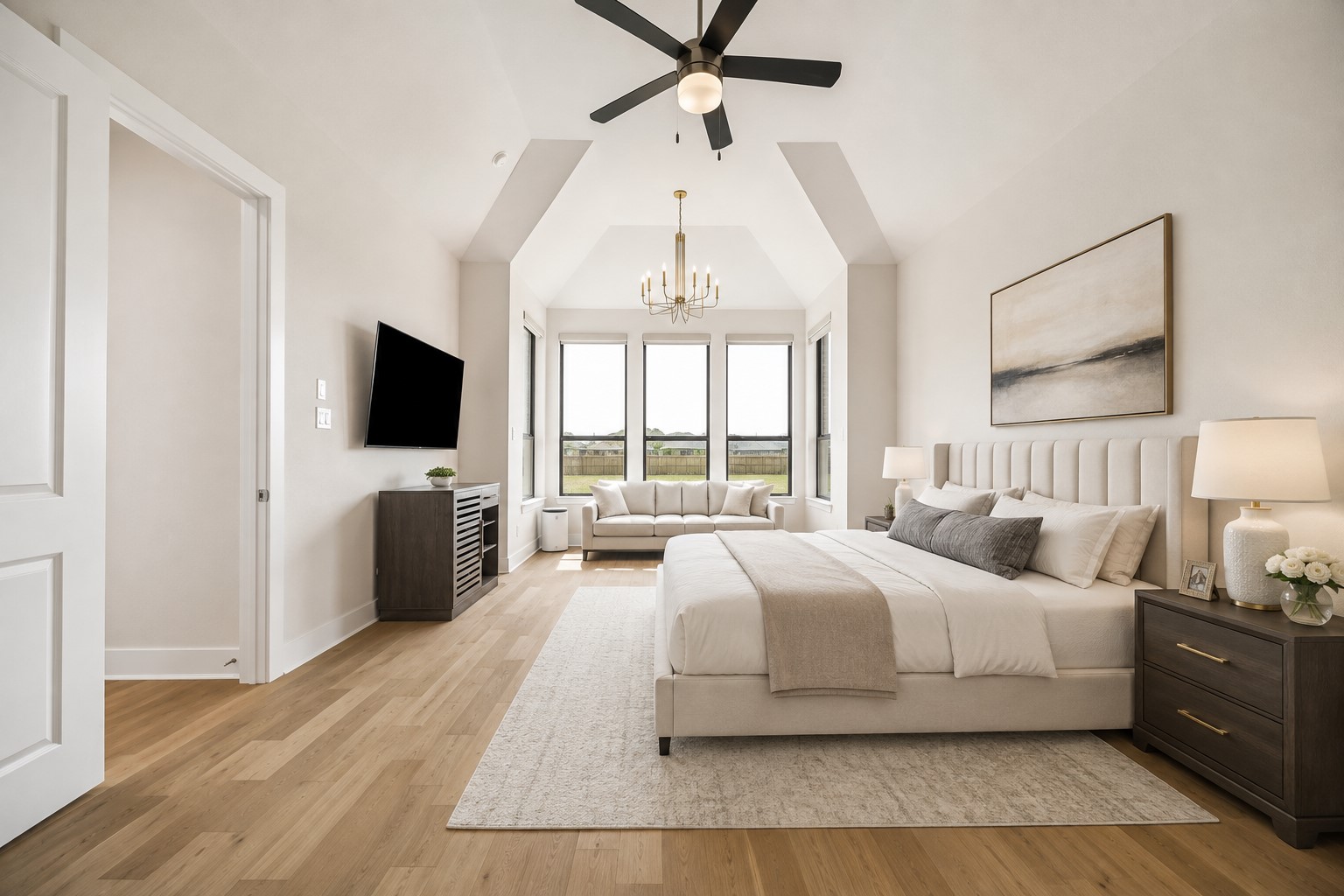 PRIMARY BEDROOM FEATURES A SPACIOUS LAYOUT, VAULTED CEILING, WOOD FLOORING, AND A WALL OF WINDOWS THAT FILLS THE ROOM WITH NATURAL LIGHT. **Virtually Staged.