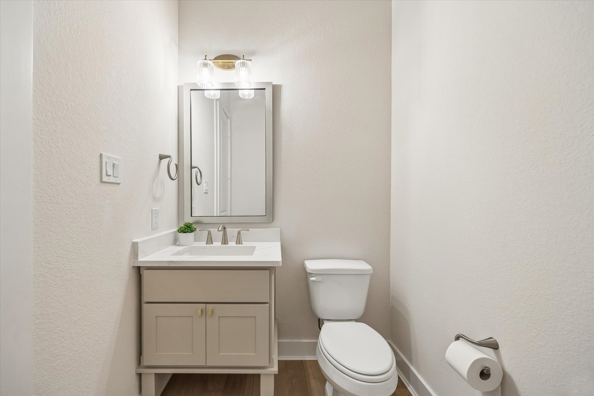 ONE OF THREE POWDER BATHROOMS, THIS ONE OFFERS A SINGLE VANITY WITH QUARTZ COUNTERTOPS, A FRAMED MIRROR, AND CONTEMPORARY FIXTURES.