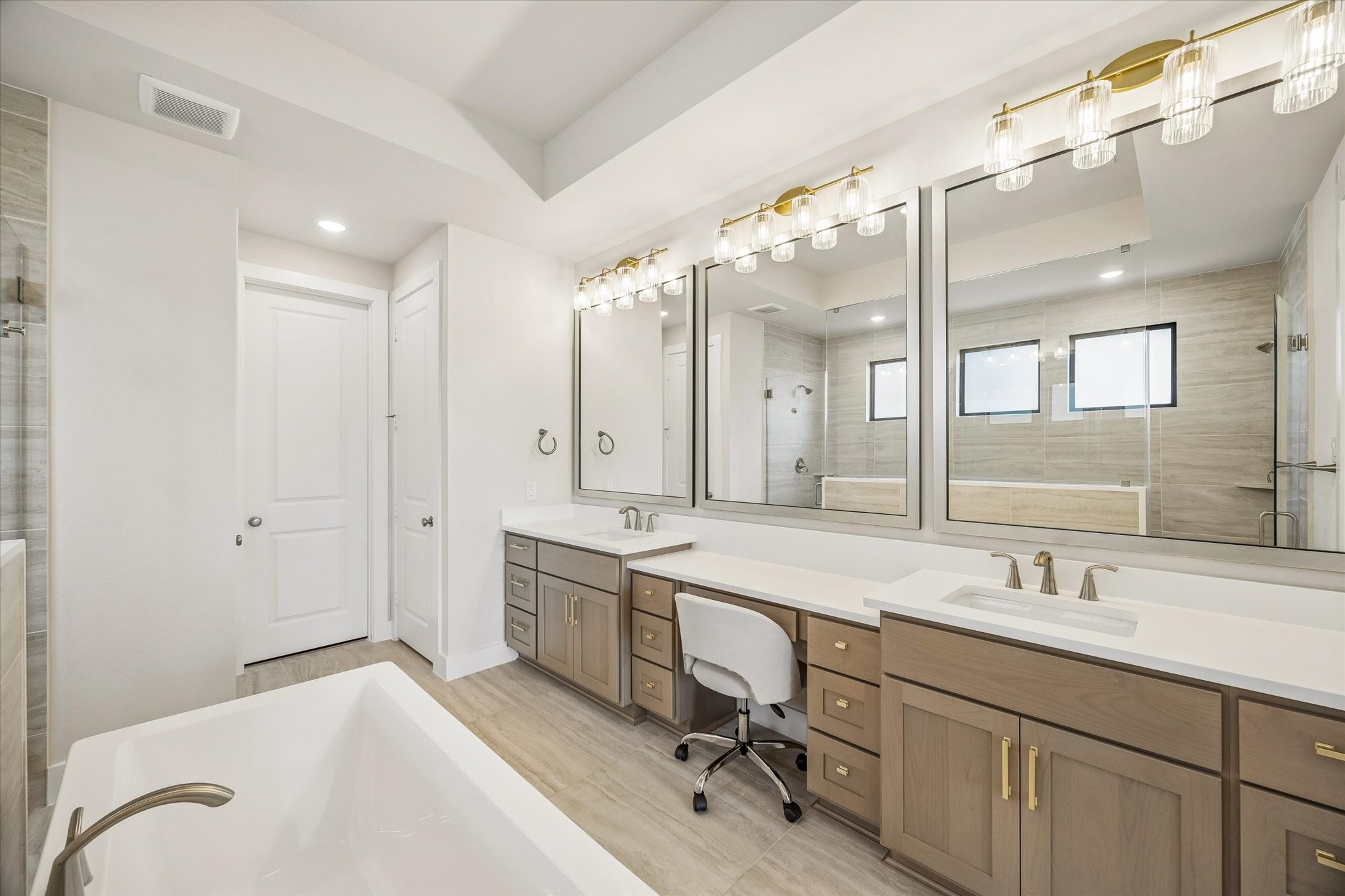 THE PRIMARY BATH INCLUDES DUAL VANITIES, GENEROUS COUNTER SPACE, AND MULTIPLE FRAMED MIRRORS WITH UPGRADED LIGHTING.