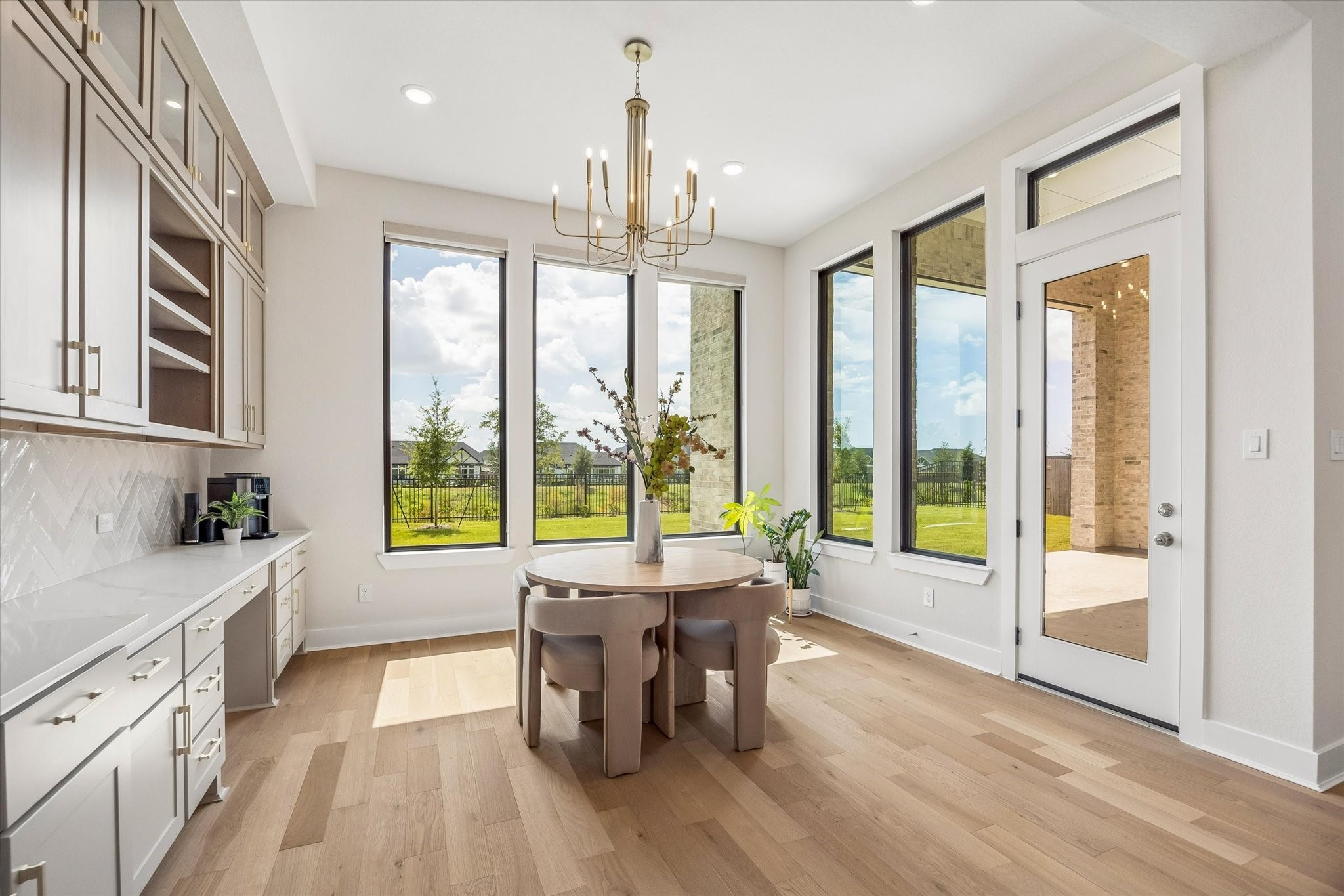 THE BREAKFAST AREA OFFERS GENEROUS NATURAL LIGHT, LARGE WINDOWS, AND DIRECT ACCESS TO THE COVERED PATIO. BUILT-IN CABINETRY AND CONTINUOUS WOOD FLOORING ADD BOTH FUNCTION AND STYLE.