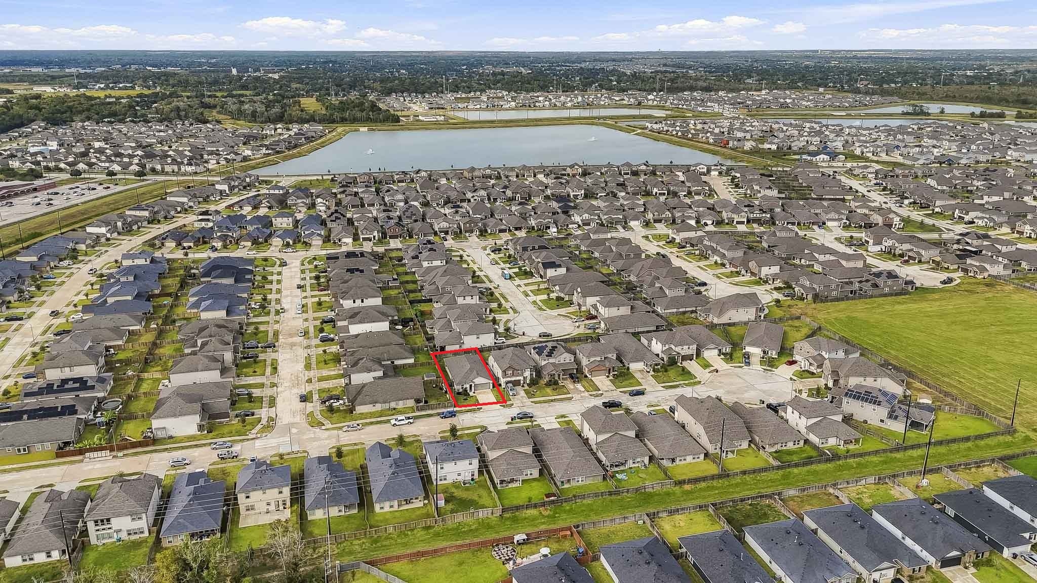This impressive aerial view showcases an expansive residential community featuring beautifully arranged homes, well-maintained streets, and spacious green areas. A large scenic lake with decorative fountains serves as a stunning centerpiece, enhancing the neighborhoods peaceful and inviting atmosphere.