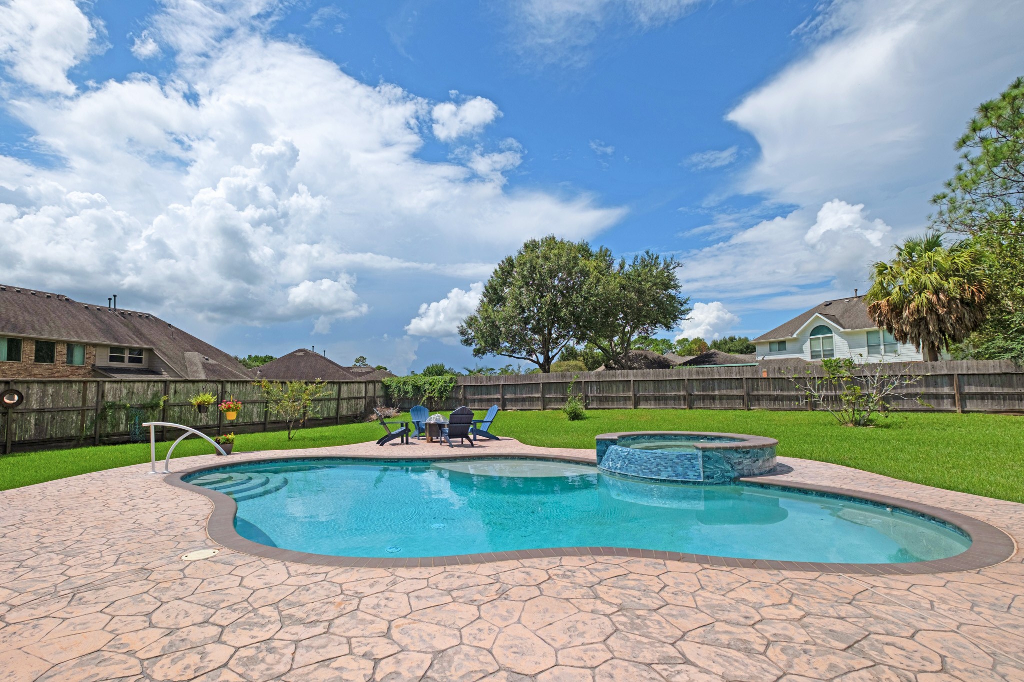 Wide open to the sky, the pool and spa sit ringed in stamped concrete with mature trees along the fence line and plenty of lawn left over.