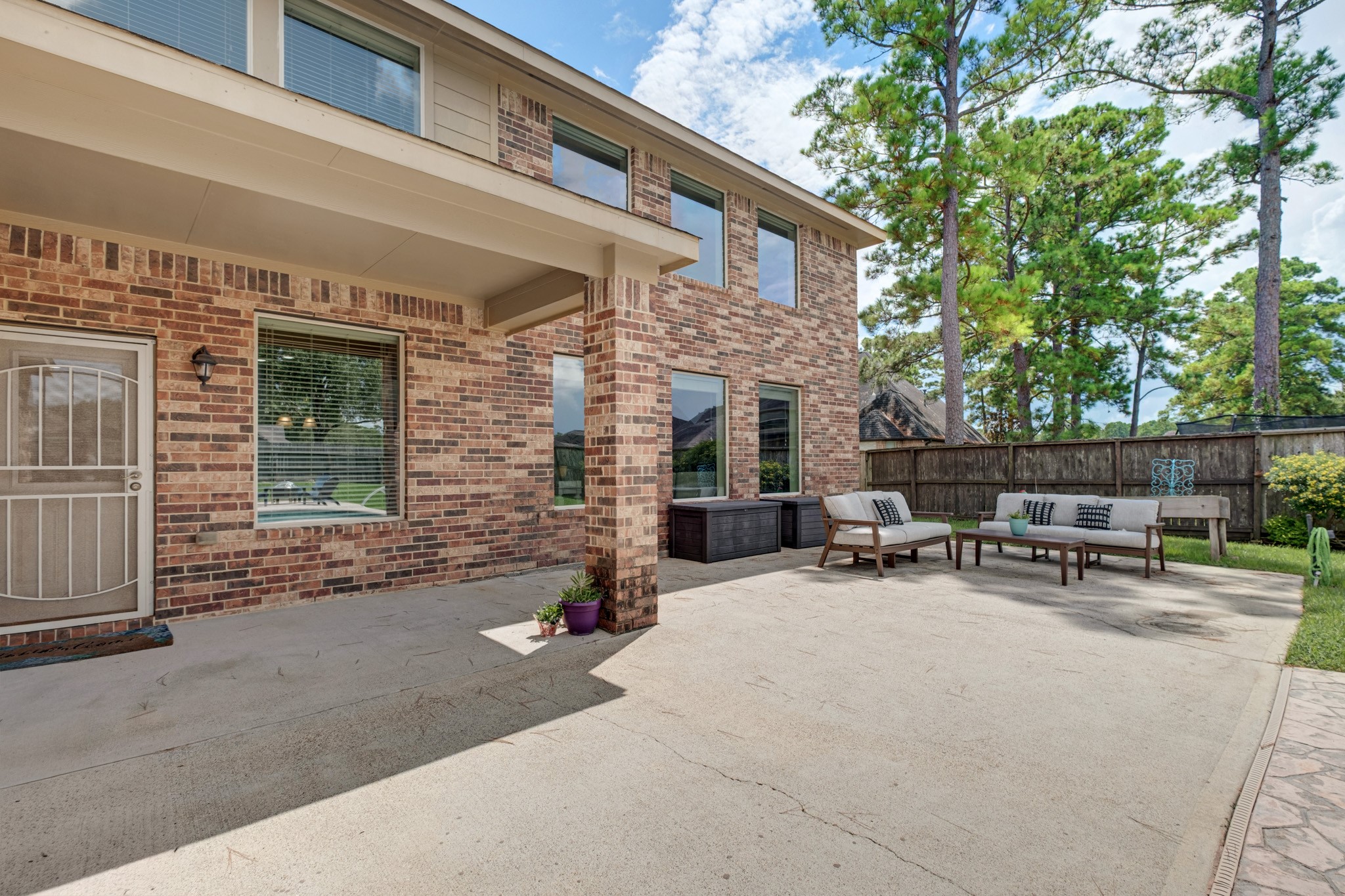 The covered patio extends off the back of the home in brick and beam, with room for a full seating group and a straight shot out to the pool deck.