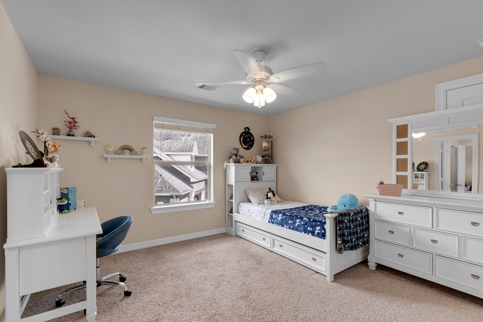 This bedroom takes the corner light, with a ceiling fan, wall shelving, and space for a desk beside the closet.