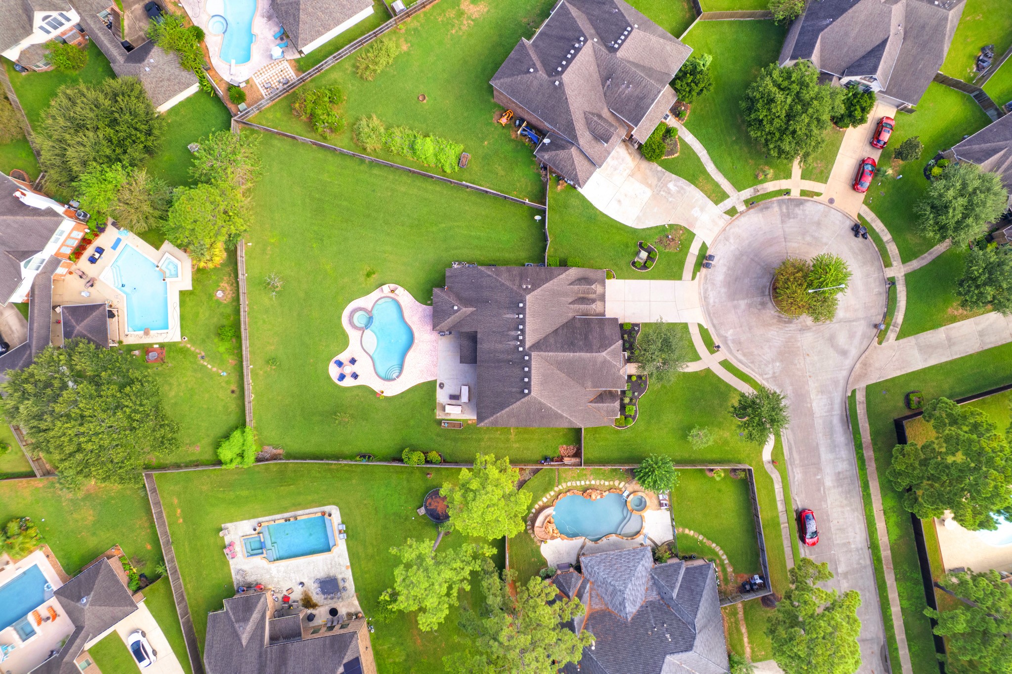 Straight down, the footprint is clear: a half-acre lot, a private pool deck set well off the fence lines, and cul-de-sac frontage with a landscaped island.