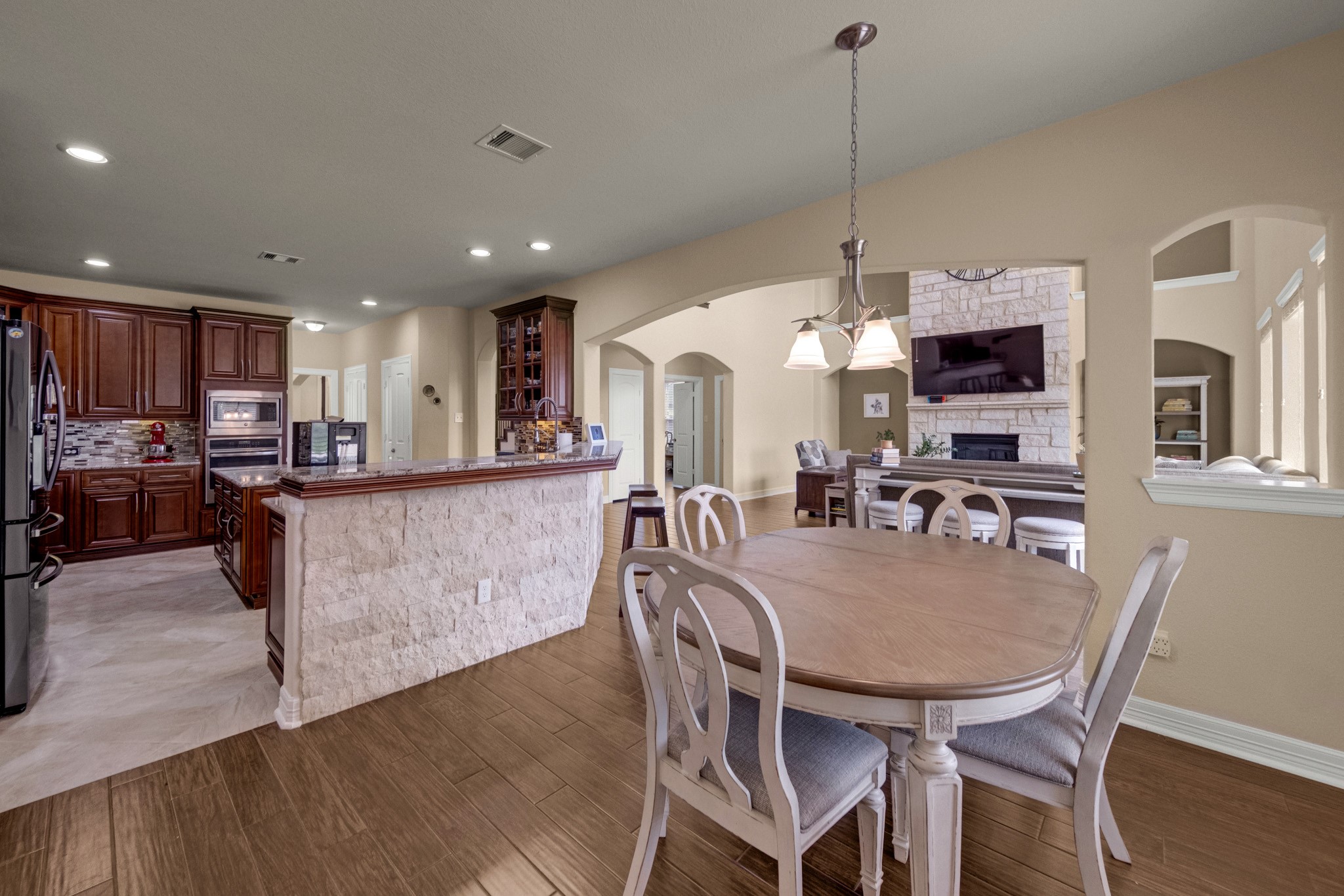 A breakfast bar in split-face silver travertine ledgestone separates the kitchen from the casual dining and keeps the whole rear of the home connected to the family room fireplace.
