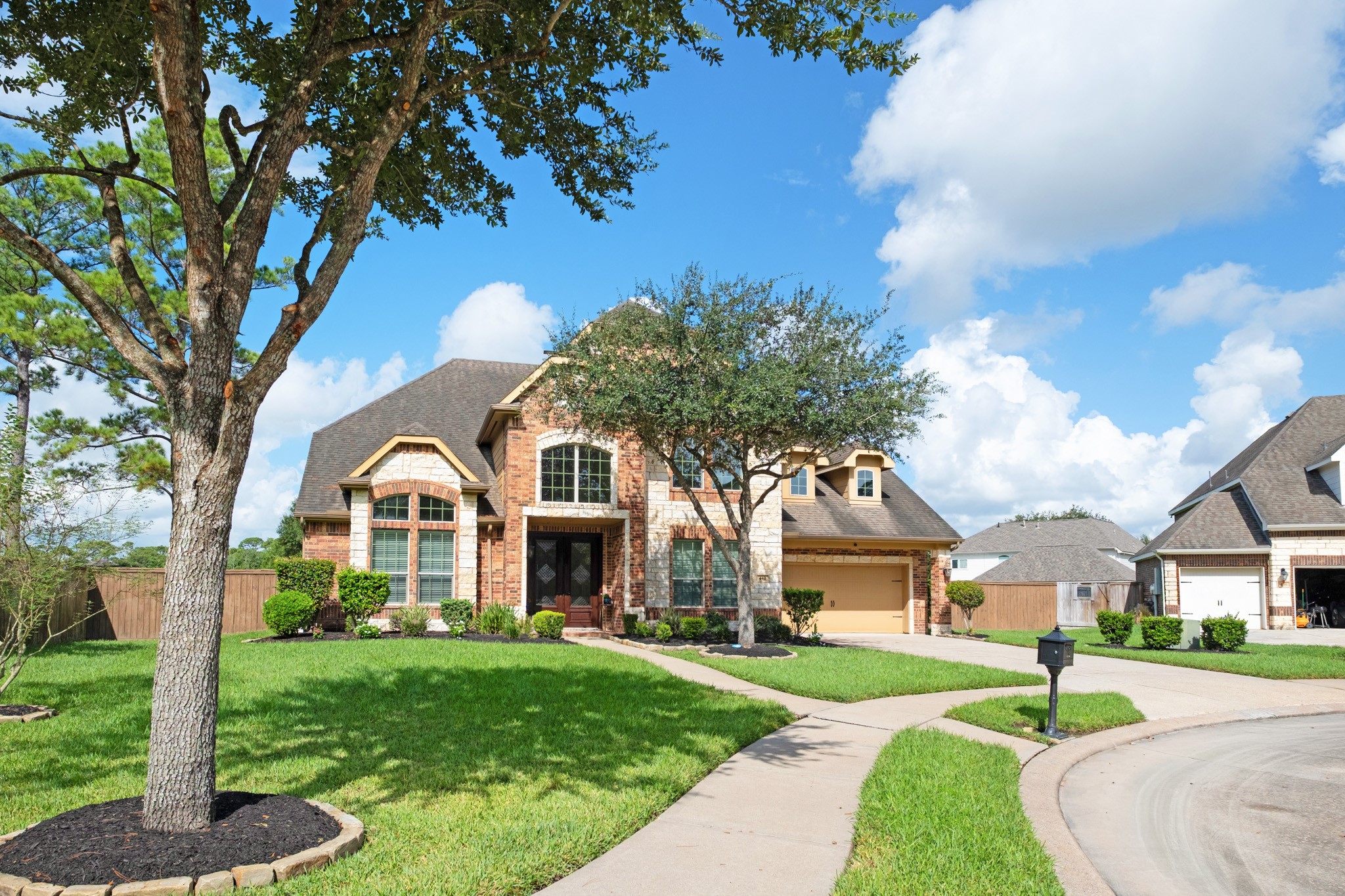 Set on the bulb of the cul-de-sac, the lot stretches wide across a deep front lawn with a mature live oak and dual walkways feeding the entry and the drive.