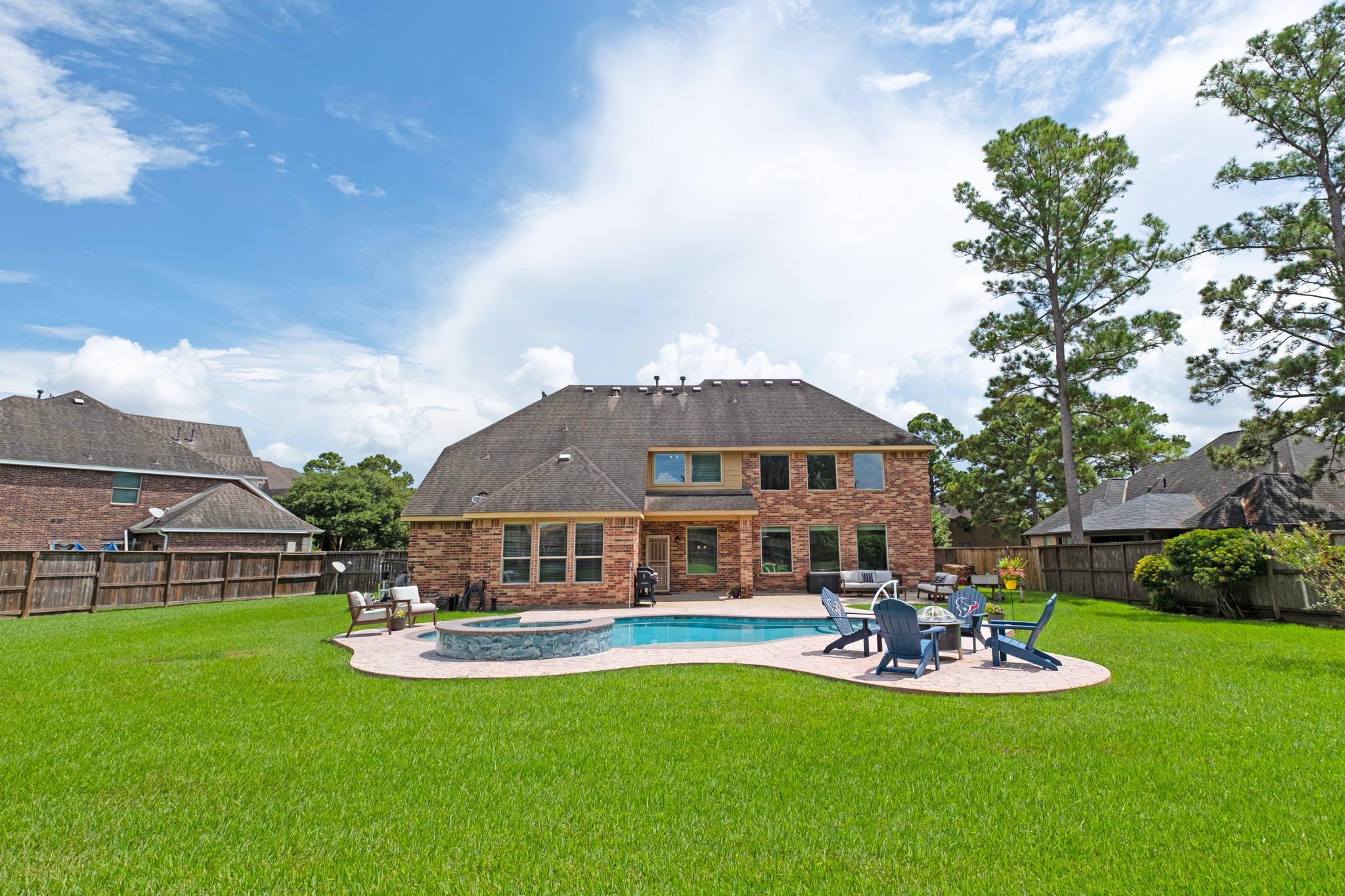 The full width of the backyard shows what the lot really offers - pool and deck on one side, a broad open run of turf on the other.