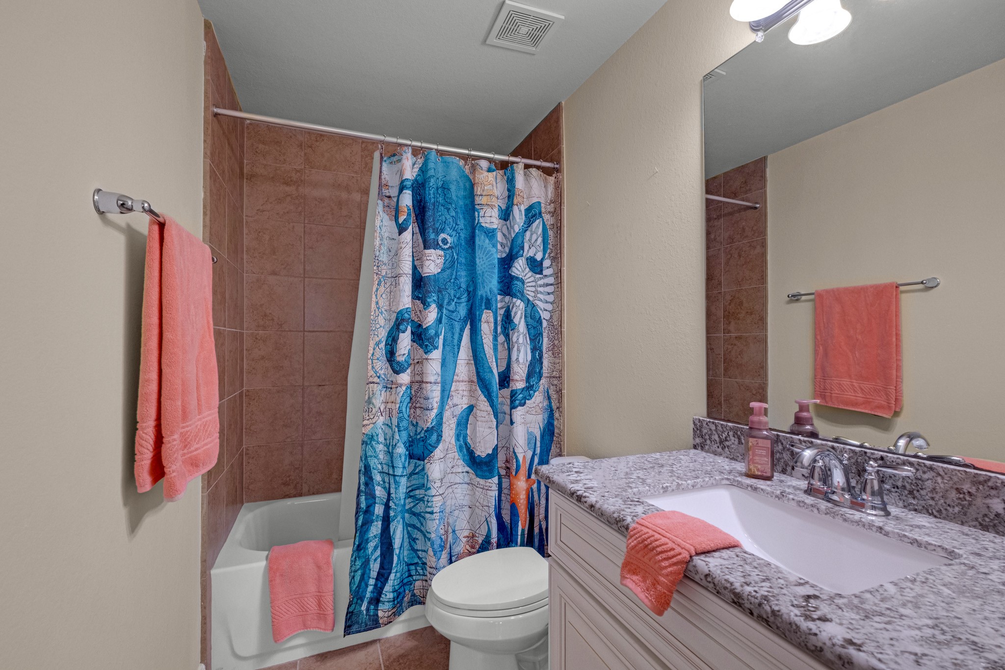 An upstairs bath keeps things practical - tiled tub-shower surround, granite vanity, and a wide mirror over the sink.