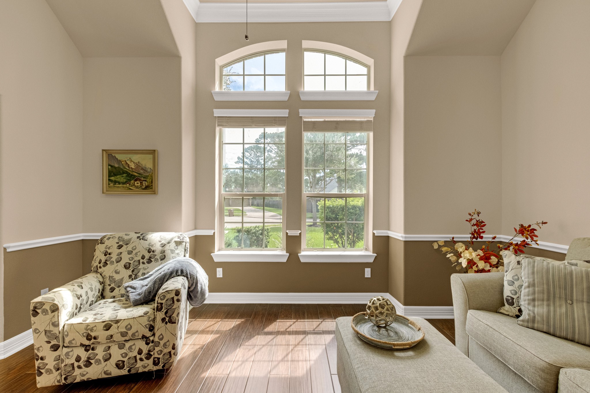 Paired arched transoms crown double-hung windows here, filling the room with morning light and giving the front rooms their cathedral feel.