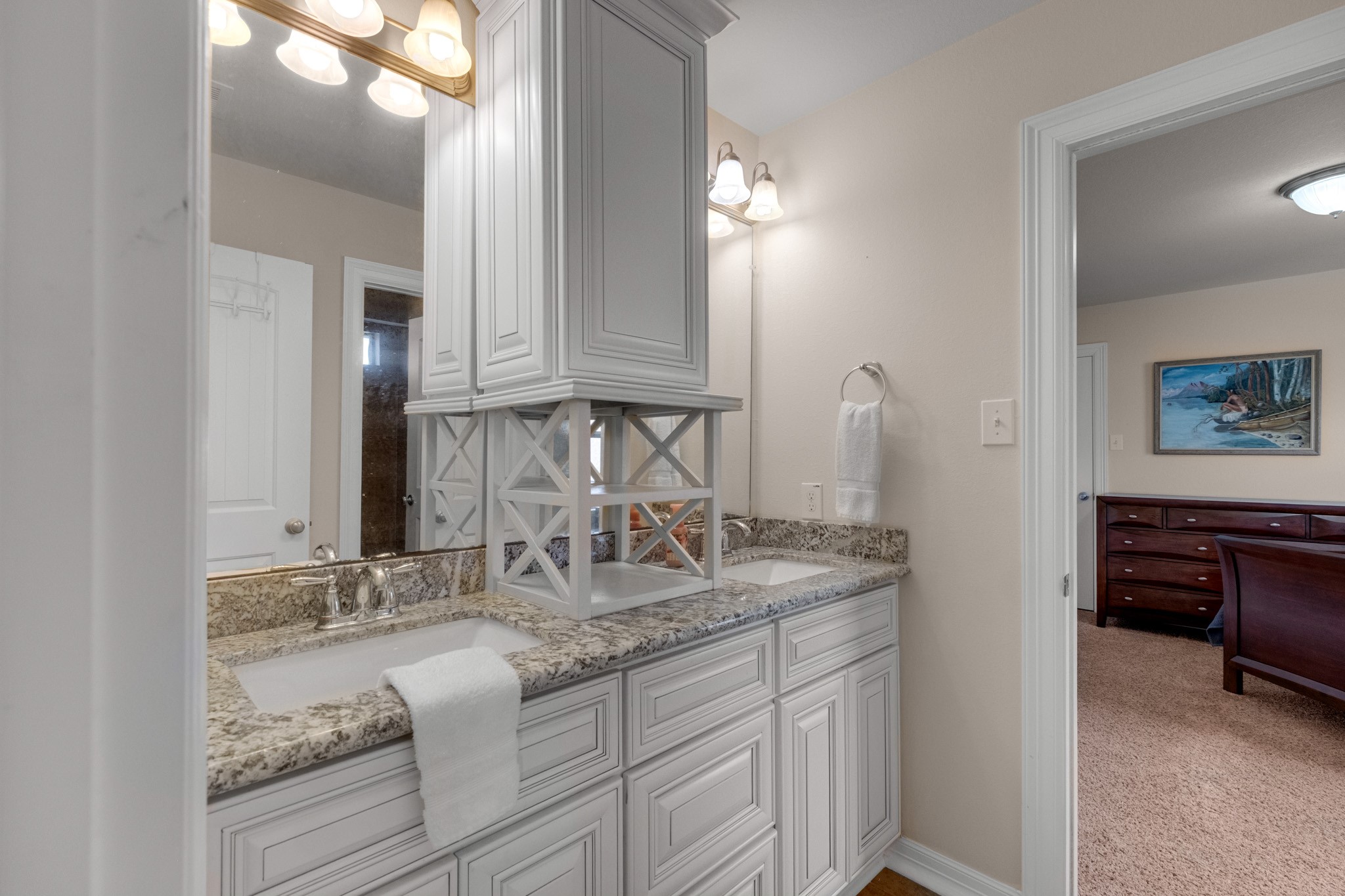 A shared bath serves the secondary bedrooms with dual sinks in granite, a center storage tower, and direct access from the bedroom side.