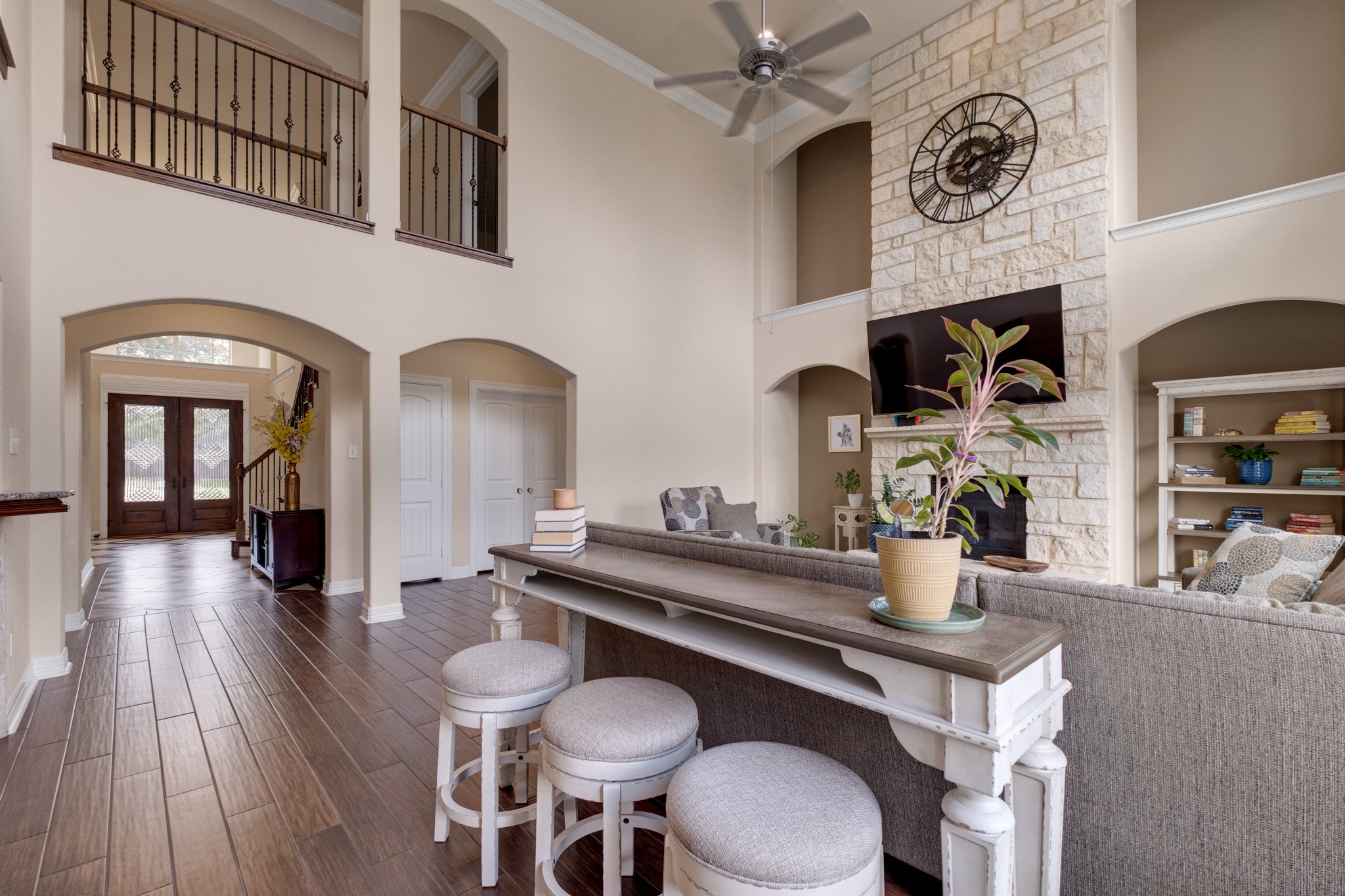 Turning toward the foyer, the arched openings and iron-railed catwalk tie the two stories together while mahogany wood tile runs continuously through the main level.